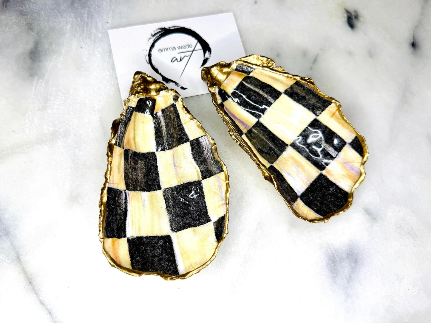 Black and gold chequered oyster shell dish with liquid gold leaf edging and glossy resin finish. A unique oyster ring dish, oyster ring tray, or shell jewellery organiser for rings, earrings, and cufflinks. This handmade trinket tray doubles as a jewellery dish or decorative coastal accent. Crafted from Dorset shells, each piece is one of a kind. A thoughtful handmade gift for weddings, anniversaries, birthdays, Christmas, bridesmaids, or new home celebrations.