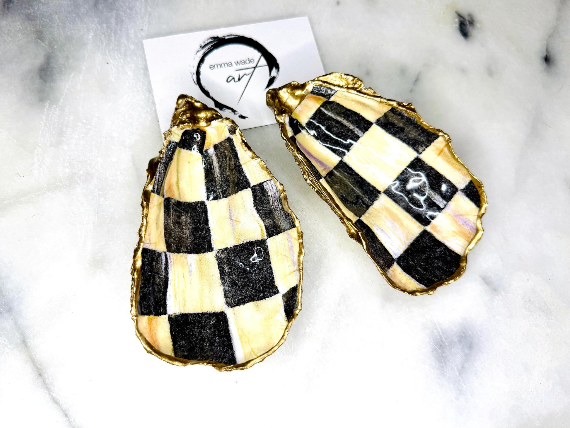 Black and gold chequered oyster shell dish with liquid gold leaf edging and glossy resin finish. A unique oyster ring dish, oyster ring tray, or shell jewellery organiser for rings, earrings, and cufflinks. This handmade trinket tray doubles as a jewellery dish or decorative coastal accent. Crafted from Dorset shells, each piece is one of a kind. A thoughtful handmade gift for weddings, anniversaries, birthdays, Christmas, bridesmaids, or new home celebrations.