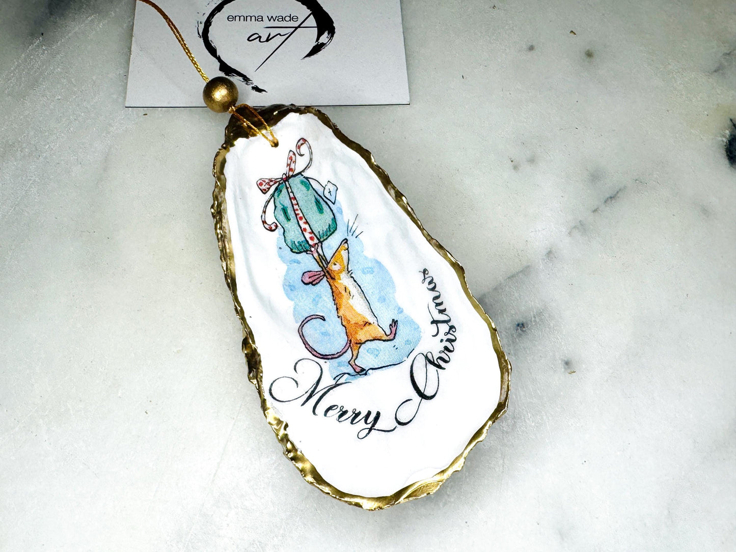 Handmade Dorset oyster shell Christmas ornament featuring a whimsical festive mouse illustration with gold leaf edging, glossy resin finish, and hanging ribbon. Coastal Christmas decoration styled as a luxury handmade oyster shell bauble and festive trinket keepsake gift.