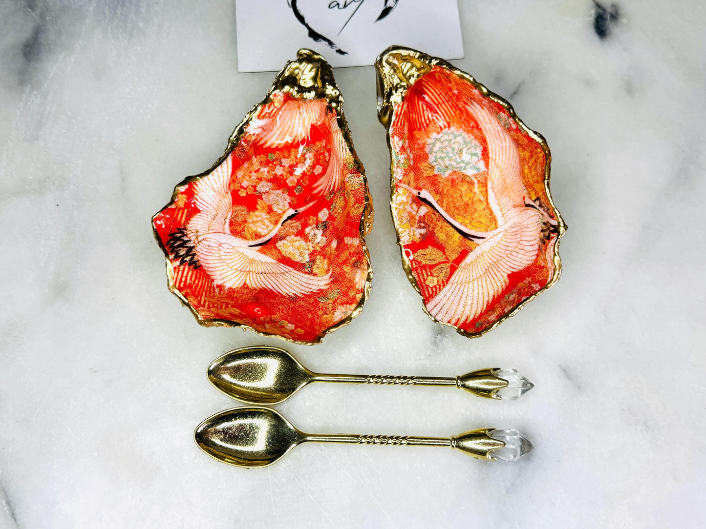 Handmade oyster shell cruet set with gold leaf trim. Salt and pepper pinch pots made from Dorset shells. Orange flamingo and Japanese kimono bird design. Sustainable and eco-friendly. A unique salt gift for weddings, anniversaries, housewarmings, or as a Christmas gift. Perfect for dinner parties, coastal home decor, or handmade UK tableware. Also ideal as spice pots, shell pots, or luxury gifts with optional gold crystal spoons.