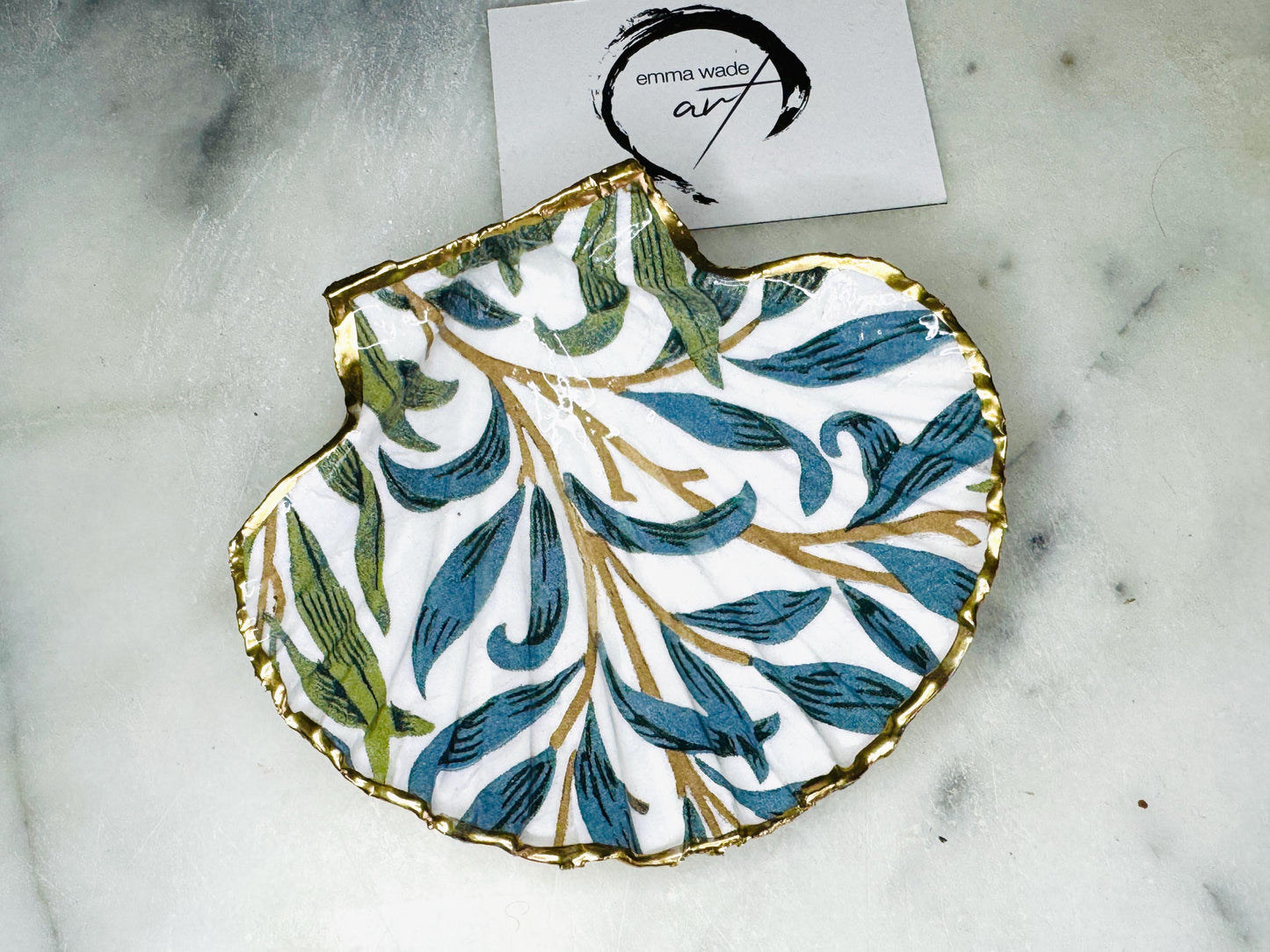 Handmade Dorset scallop shell trinket dish featuring William Morris Willow Bough design in soft blue and green tones. Decorative shell jewellery dish finished with hand-applied liquid gold leaf edging and glossy resin. Coastal inspired ring holder with botanical Arts and Crafts pattern and natural shell shape, styled as elegant bathroom décor and heritage home accessory.