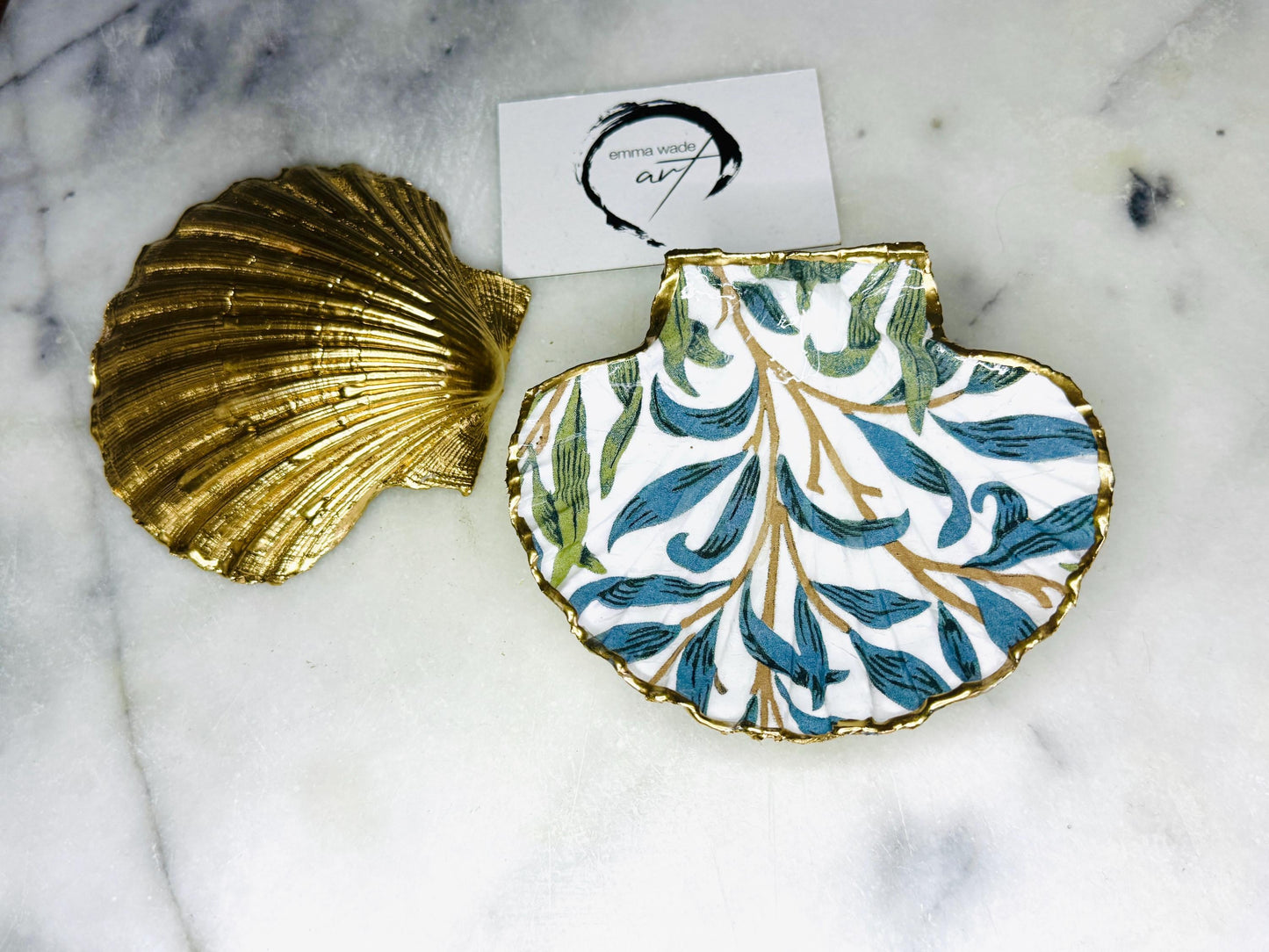 Handmade Dorset scallop shell trinket dish featuring William Morris Willow Bough design in soft blue and green tones. Decorative shell jewellery dish finished with hand-applied liquid gold leaf edging and glossy resin. Coastal inspired ring holder with botanical Arts and Crafts pattern and natural shell shape, styled as elegant bathroom décor and heritage home accessory.