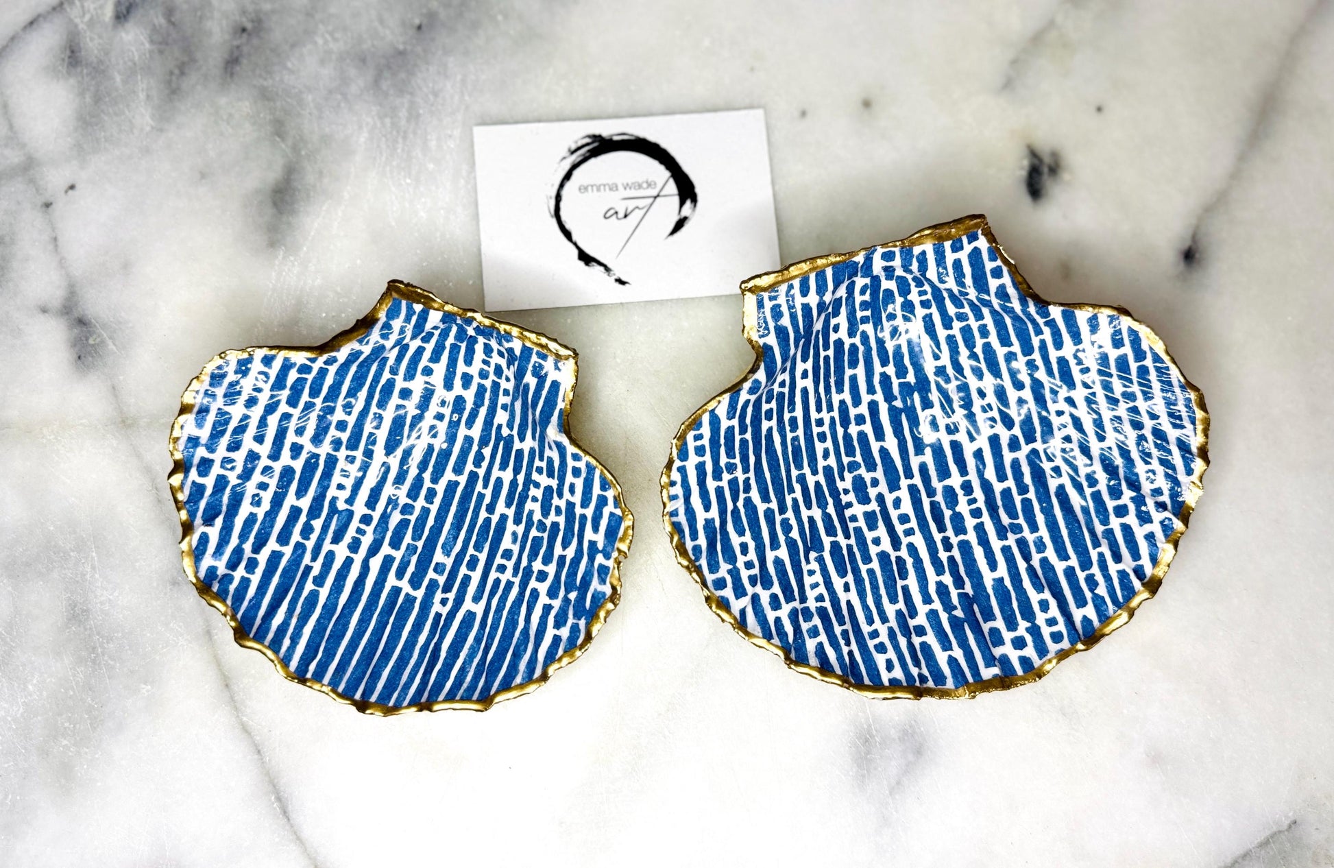 Handmade blue and white scallop shell trinket dish with gold leaf edging, crafted from a genuine Dorset shell and sealed with glossy resin. Coastal ring dish and jewellery holder featuring elegant blue line design, displayed in gift packaging. Artisan shell decor handmade in Surrey, perfect for coastal home styling, wedding gifts or nautical themed interiors.