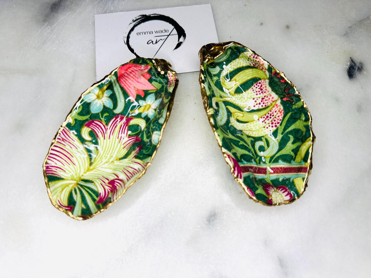Hand finished Dorset oyster shell trinket dish featuring William Morris Golden Lily design, edged with real gold leaf and sealed with high gloss resin. Decorative jewellery dish styled on marble background, ideal as ring holder, coastal home decor accent or luxury wedding and bridesmaid gift.