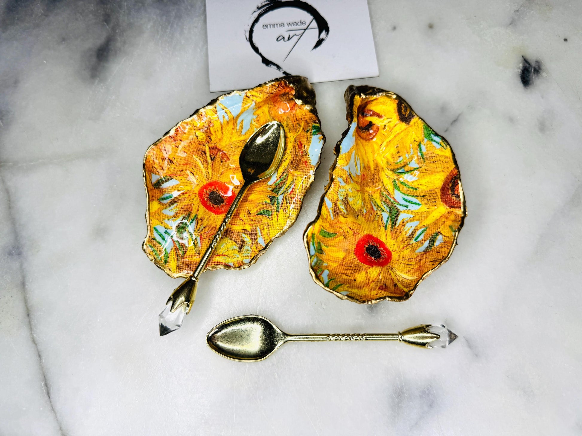 Pair of oyster shell salt and pepper dishes inspired by Vincent Van Gogh Sunflowers. Handmade from natural Dorset shells, each dish is decorated with a sunflower design, trimmed with gold leaf, and sealed for a glossy finish. Approx. 9–10cm with natural variations in shape and depth. Can be used as salt pinch pots, trinket trays, or decorative shell dishes. Optional gold crystal spoons add a luxury touch. A unique handmade gift for weddings, anniversaries, birthdays, or Christmas.