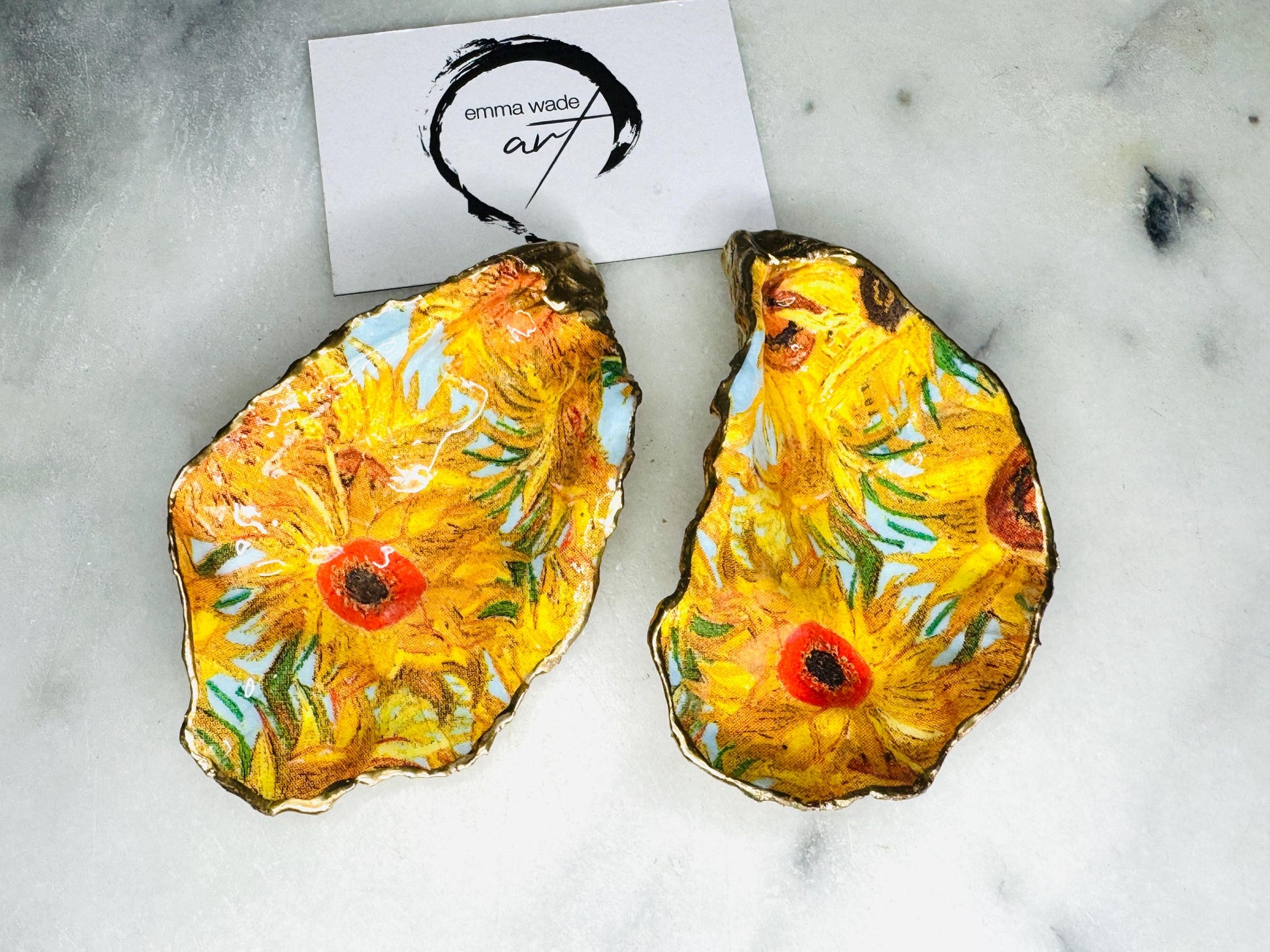 Pair of oyster shell salt and pepper dishes inspired by Vincent Van Gogh Sunflowers. Handmade from natural Dorset shells, each dish is decorated with a sunflower design, trimmed with gold leaf, and sealed for a glossy finish. Approx. 9–10cm with natural variations in shape and depth. Can be used as salt pinch pots, trinket trays, or decorative shell dishes. Optional gold crystal spoons add a luxury touch. A unique handmade gift for weddings, anniversaries, birthdays, or Christmas.