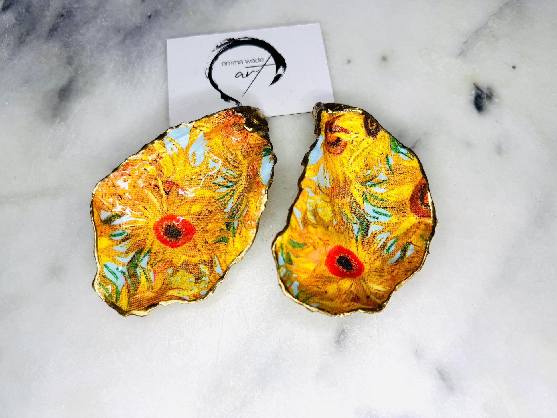 Pair of oyster shell salt and pepper dishes inspired by Vincent Van Gogh Sunflowers. Handmade from natural Dorset shells, each dish is decorated with a sunflower design, trimmed with gold leaf, and sealed for a glossy finish. Approx. 9–10cm with natural variations in shape and depth. Can be used as salt pinch pots, trinket trays, or decorative shell dishes. Optional gold crystal spoons add a luxury touch. A unique handmade gift for weddings, anniversaries, birthdays, or Christmas.