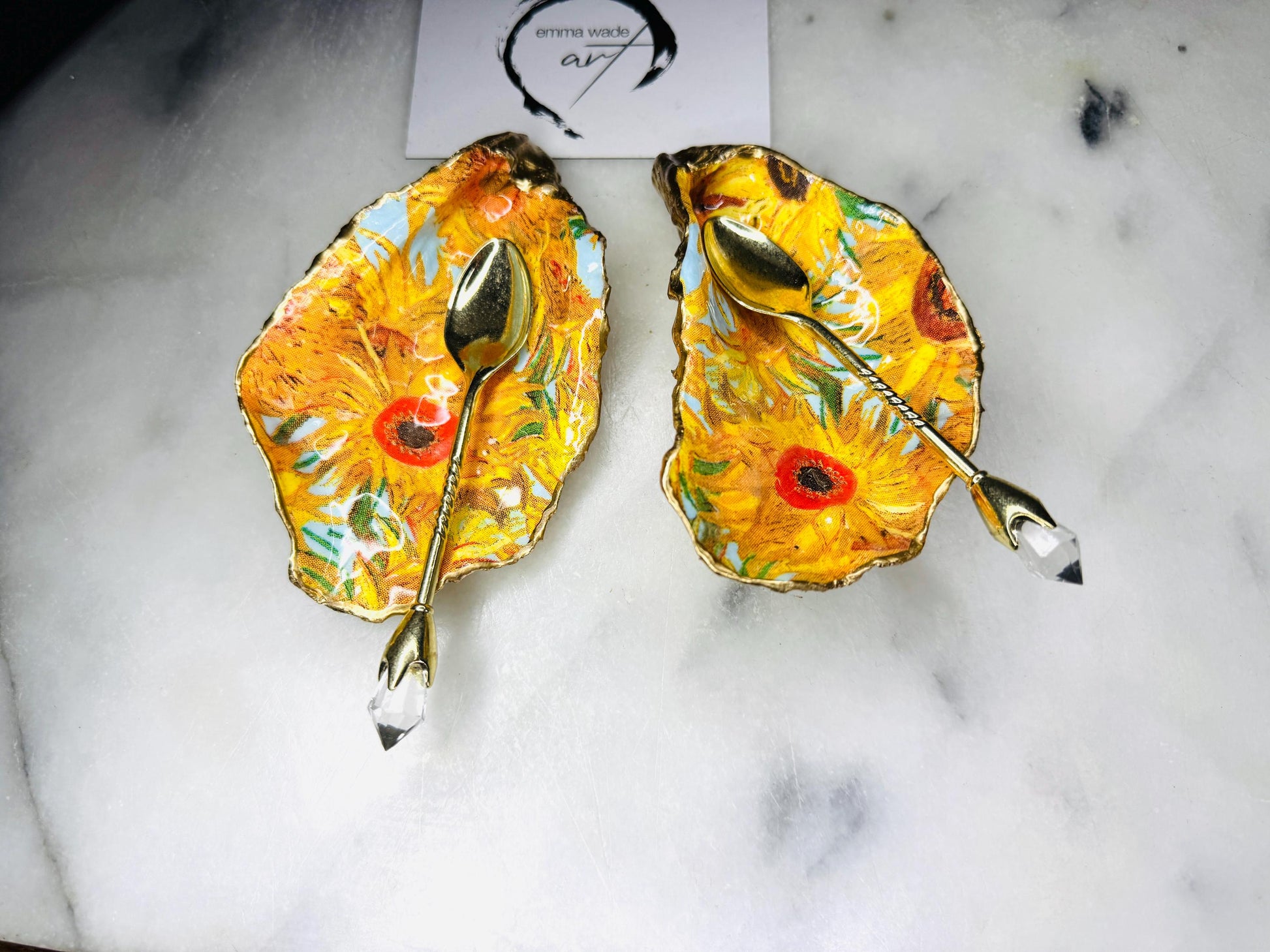 Pair of oyster shell salt and pepper dishes inspired by Vincent Van Gogh Sunflowers. Handmade from natural Dorset shells, each dish is decorated with a sunflower design, trimmed with gold leaf, and sealed for a glossy finish. Approx. 9–10cm with natural variations in shape and depth. Can be used as salt pinch pots, trinket trays, or decorative shell dishes. Optional gold crystal spoons add a luxury touch. A unique handmade gift for weddings, anniversaries, birthdays, or Christmas.