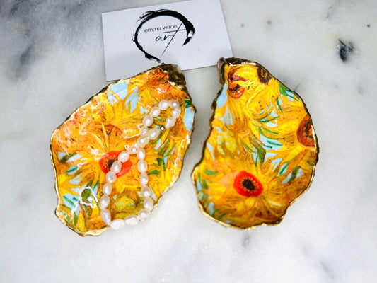 Hand-painted Vincent Van Gogh Sunflowers oyster shell trinket dish with hand-applied liquid gold leaf edging and high gloss resin finish. Natural Dorset oyster shell jewellery holder featuring vibrant yellow sunflower design, styled on marble surface as a ring dish, coastal decor accent and luxury handmade gift.