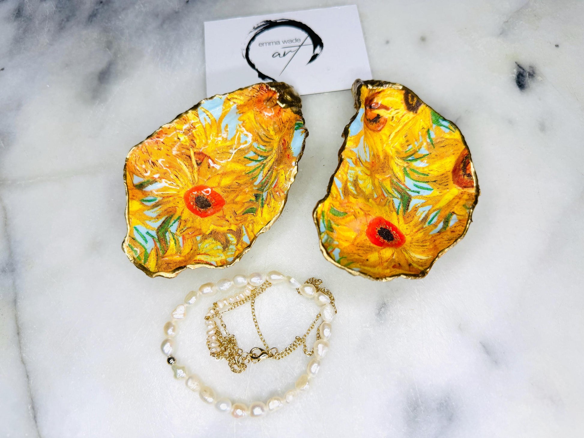 Hand-painted Vincent Van Gogh Sunflowers oyster shell trinket dish with hand-applied liquid gold leaf edging and high gloss resin finish. Natural Dorset oyster shell jewellery holder featuring vibrant yellow sunflower design, styled on marble surface as a ring dish, coastal decor accent and luxury handmade gift.