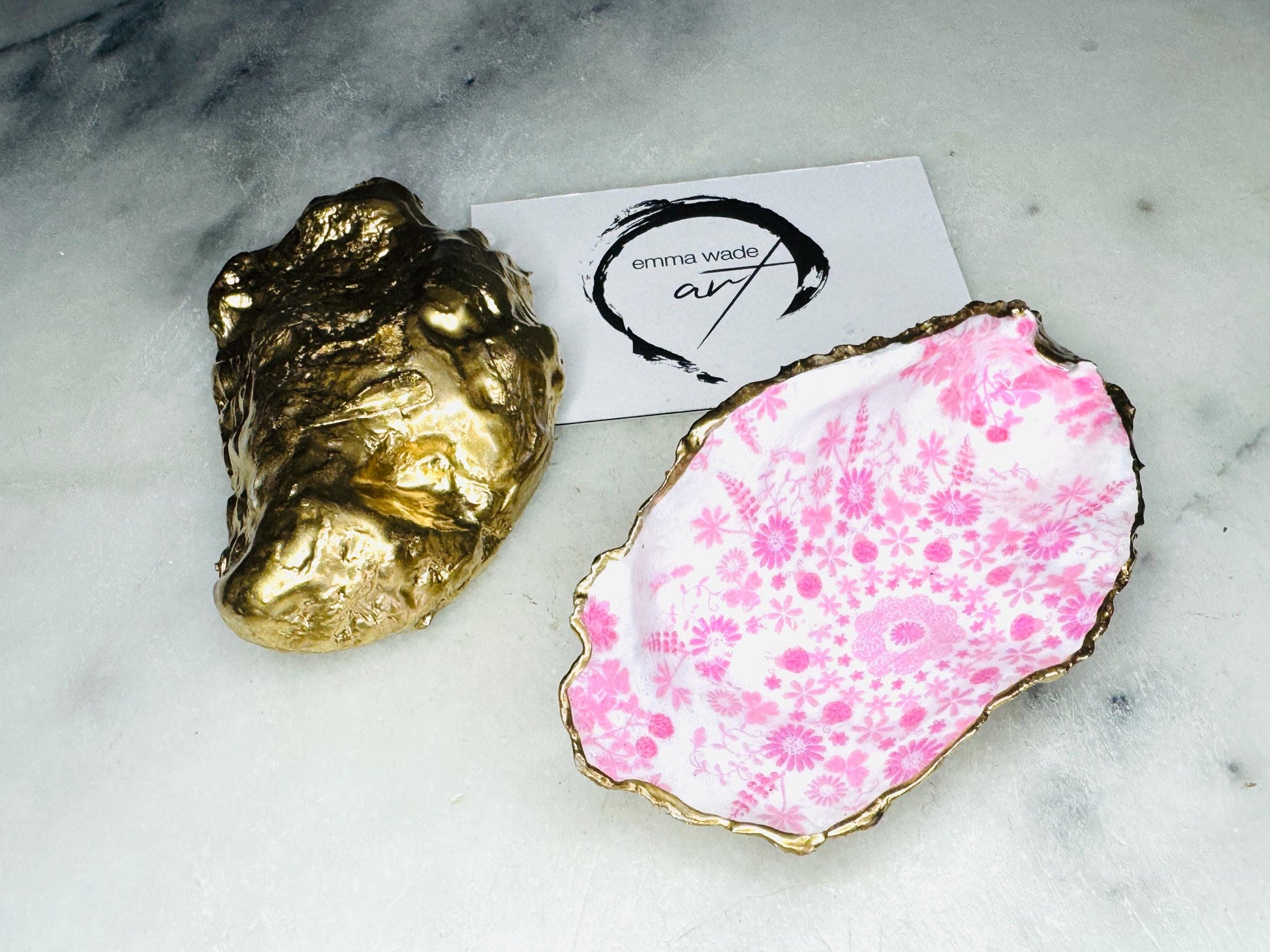 Floral oyster shell ring holder with pink lily design and gold leaf edge. Handmade shell jewellery dish, ideal as a trinket tray or shell ring tray. Each shell is unique, approx. 9–11cm. Perfect for displaying rings, earrings, or cufflinks, or as a decorative piece in the bathroom or bedroom. A versatile gift for weddings, anniversaries, bridesmaids, or new homes. Can also be used as a tealight holder, spoon rest, or small salt and pepper dish.