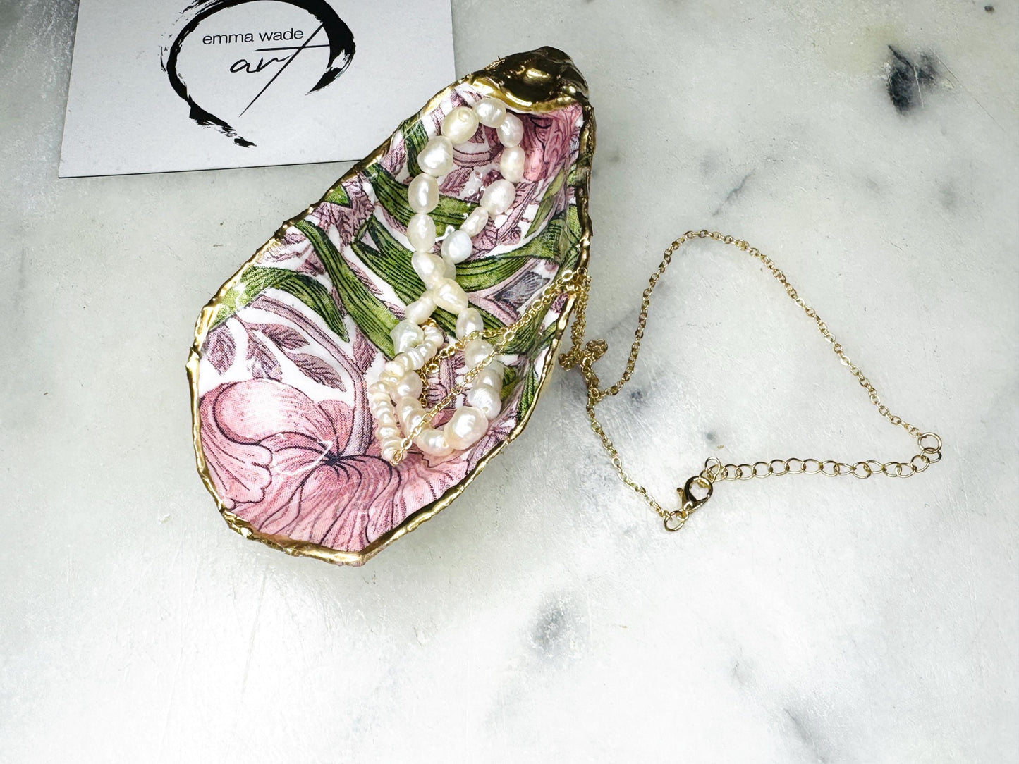 Single handcrafted Dorset oyster shell trinket dish featuring the William Morris Pink Pimpernel design in pink and green tones, edged with liquid gold leaf and sealed in glossy resin. Sold individually, this natural oyster shell jewellery holder is ideal for rings or earrings and makes a unique coastal gift or wedding favour.