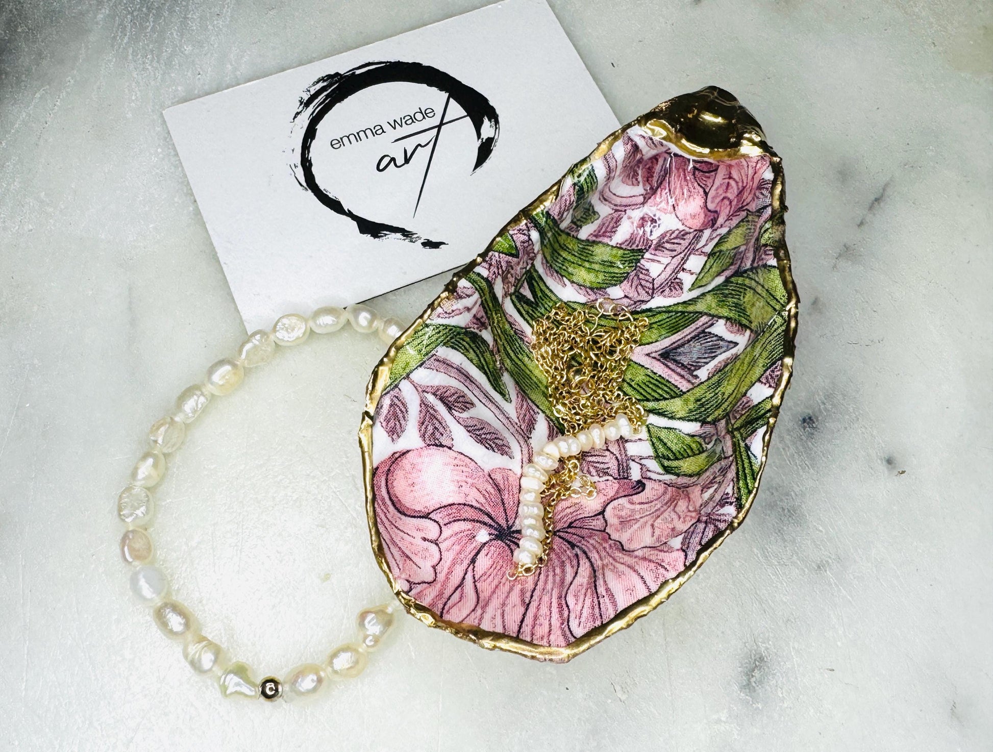 Single handcrafted Dorset oyster shell trinket dish featuring the William Morris Pink Pimpernel design in pink and green tones, edged with liquid gold leaf and sealed in glossy resin. Sold individually, this natural oyster shell jewellery holder is ideal for rings or earrings and makes a unique coastal gift or wedding favour.