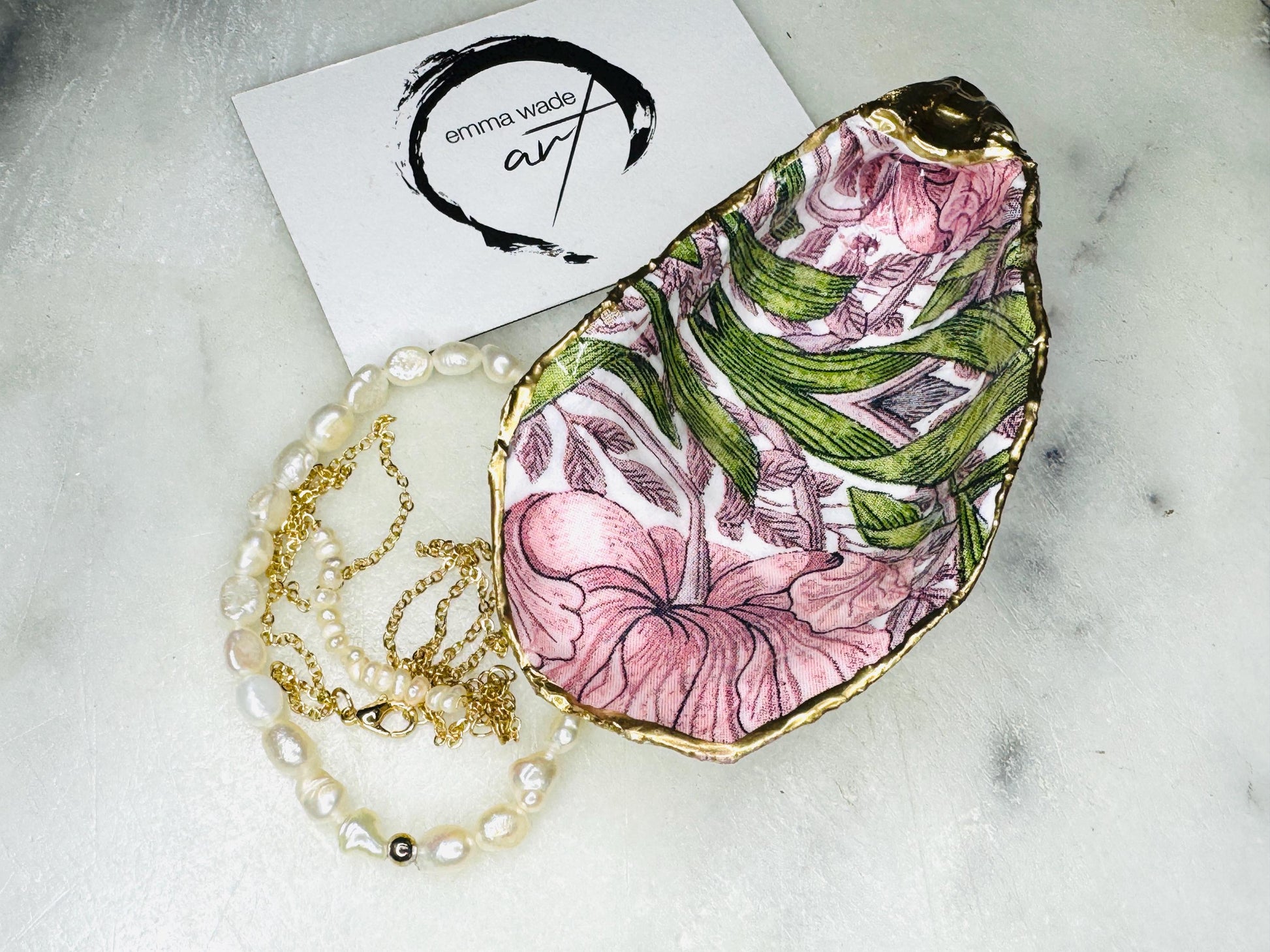 Single handcrafted Dorset oyster shell trinket dish featuring the William Morris Pink Pimpernel design in pink and green tones, edged with liquid gold leaf and sealed in glossy resin. Sold individually, this natural oyster shell jewellery holder is ideal for rings or earrings and makes a unique coastal gift or wedding favour.