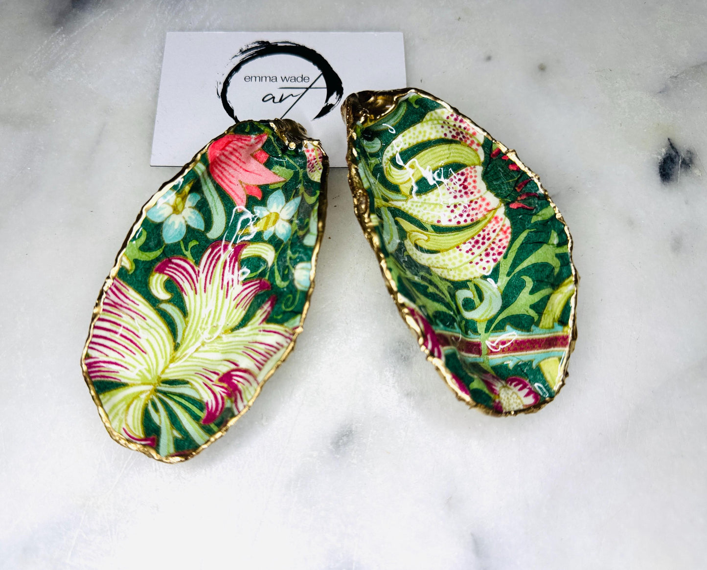 Hand finished Dorset oyster shell trinket dish featuring William Morris Golden Lily design, edged with real gold leaf and sealed with high gloss resin. Decorative jewellery dish styled on marble background, ideal as ring holder, coastal home decor accent or luxury wedding and bridesmaid gift.