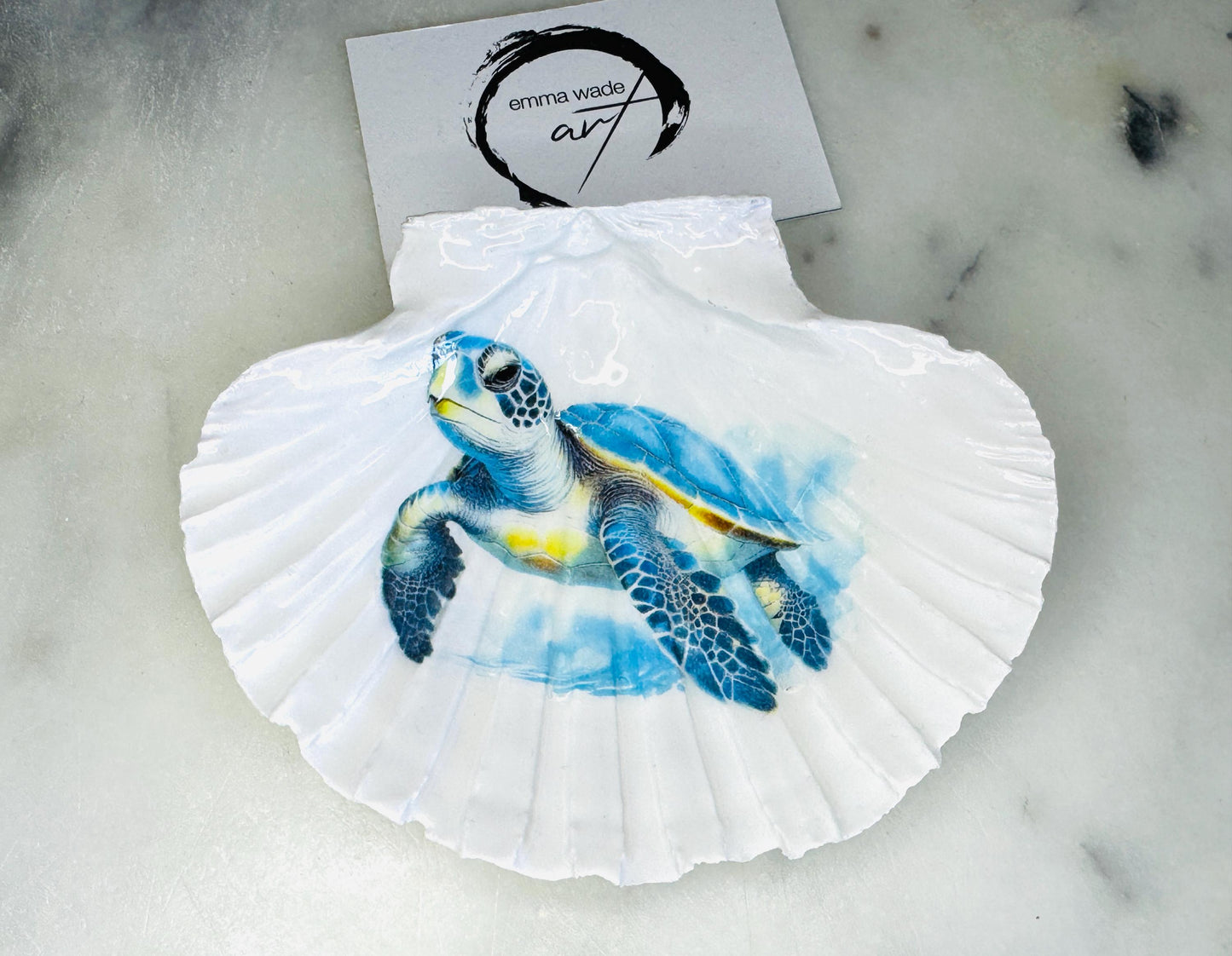 Handmade scallop shell trinket dish featuring a blue sea turtle illustration, finished with high gloss crystal resin and optional gilded gold leaf edges. Coastal home decor shell dish for jewellery, rings, trinkets or bedside storage. Nautical ocean inspired decorative shell, handmade in the UK using sustainably sourced shells from the Dorset coastline. Ideal coastal gift for ocean lovers and beach house interiors.
