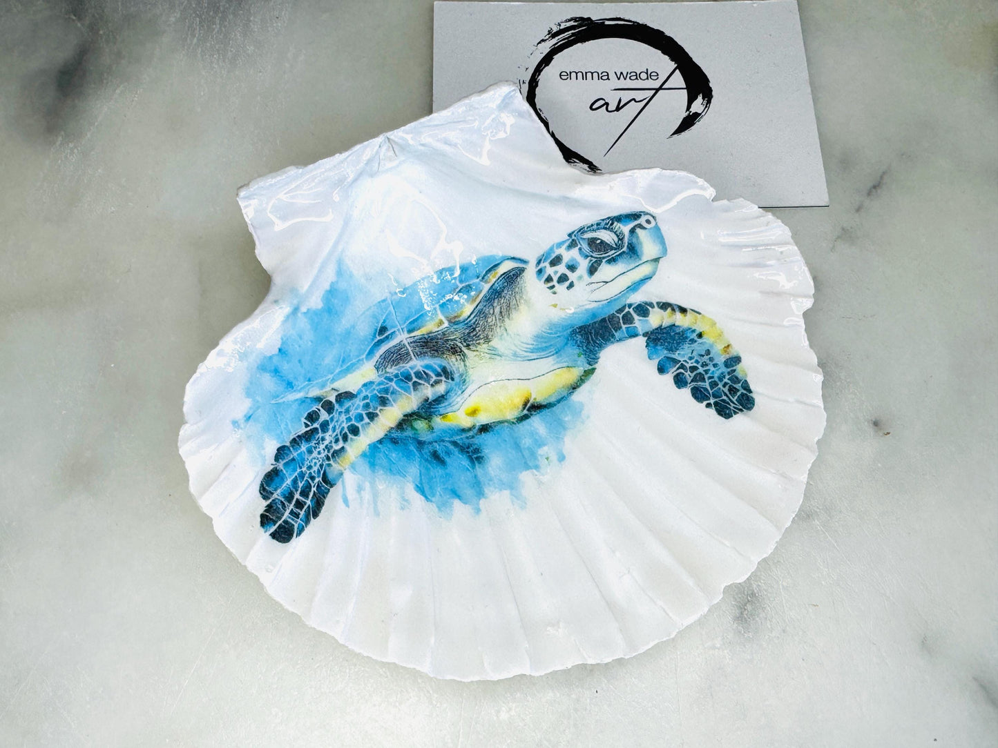 Handmade scallop shell trinket dish featuring a blue sea turtle illustration, finished with high gloss crystal resin and optional gilded gold leaf edges. Coastal home decor shell dish for jewellery, rings, trinkets or bedside storage. Nautical ocean inspired decorative shell, handmade in the UK using sustainably sourced shells from the Dorset coastline. Ideal coastal gift for ocean lovers and beach house interiors.