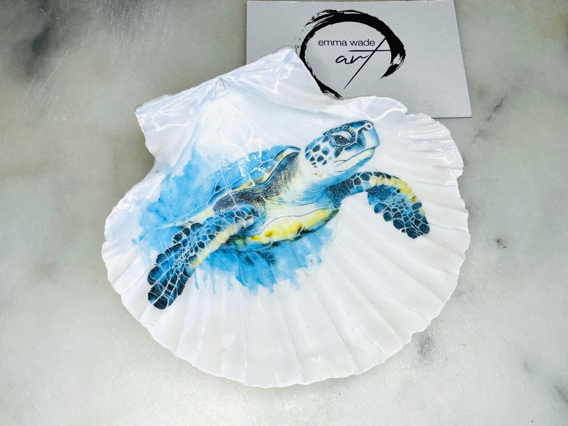 Handmade scallop shell trinket dish featuring a blue sea turtle illustration, finished with high gloss crystal resin and optional gilded gold leaf edges. Coastal home decor shell dish for jewellery, rings, trinkets or bedside storage. Nautical ocean inspired decorative shell, handmade in the UK using sustainably sourced shells from the Dorset coastline. Ideal coastal gift for ocean lovers and beach house interiors.