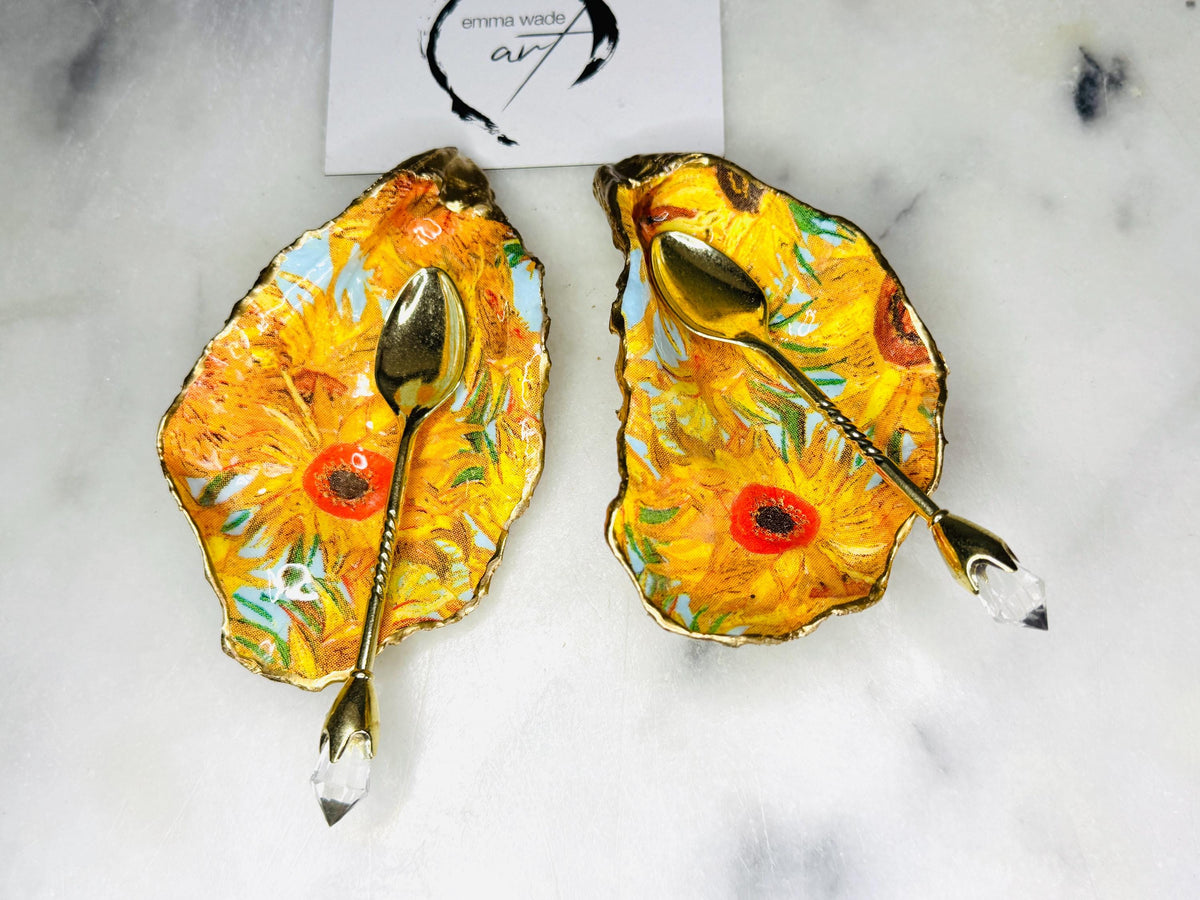 Pair of oyster shell salt and pepper dishes inspired by Vincent Van Gogh Sunflowers. Handmade from natural Dorset shells, each dish is decorated with a sunflower design, trimmed with gold leaf, and sealed for a glossy finish. Approx. 9–10cm with natural variations in shape and depth. Can be used as salt pinch pots, trinket trays, or decorative shell dishes. Optional gold crystal spoons add a luxury touch. A unique handmade gift for weddings, anniversaries, birthdays, or Christmas.