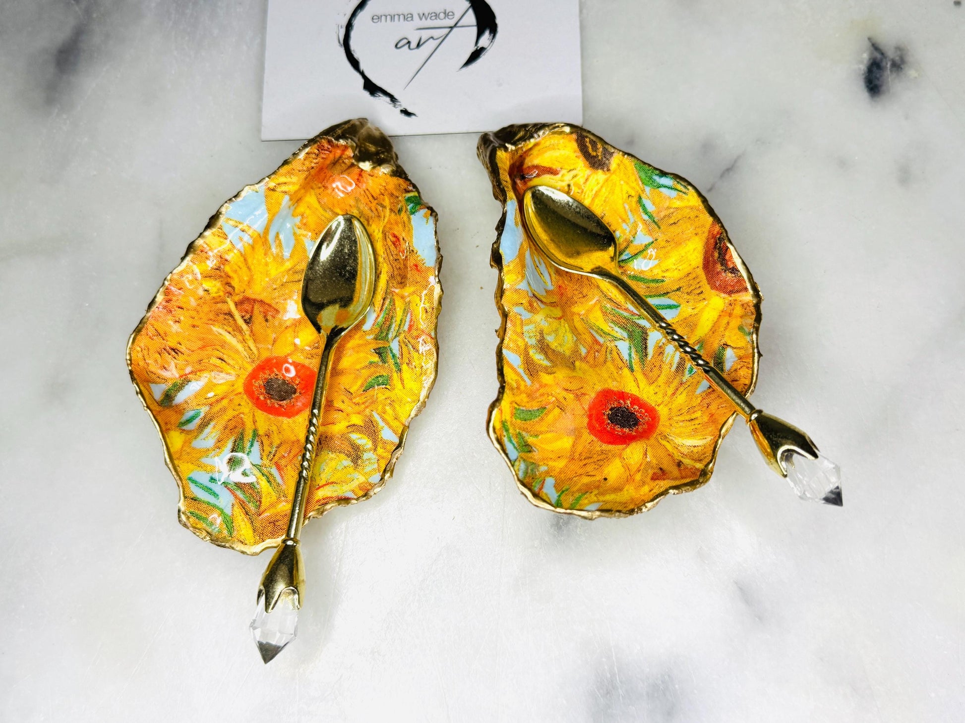 Pair of oyster shell salt and pepper dishes inspired by Vincent Van Gogh Sunflowers. Handmade from natural Dorset shells, each dish is decorated with a sunflower design, trimmed with gold leaf, and sealed for a glossy finish. Approx. 9–10cm with natural variations in shape and depth. Can be used as salt pinch pots, trinket trays, or decorative shell dishes. Optional gold crystal spoons add a luxury touch. A unique handmade gift for weddings, anniversaries, birthdays, or Christmas.