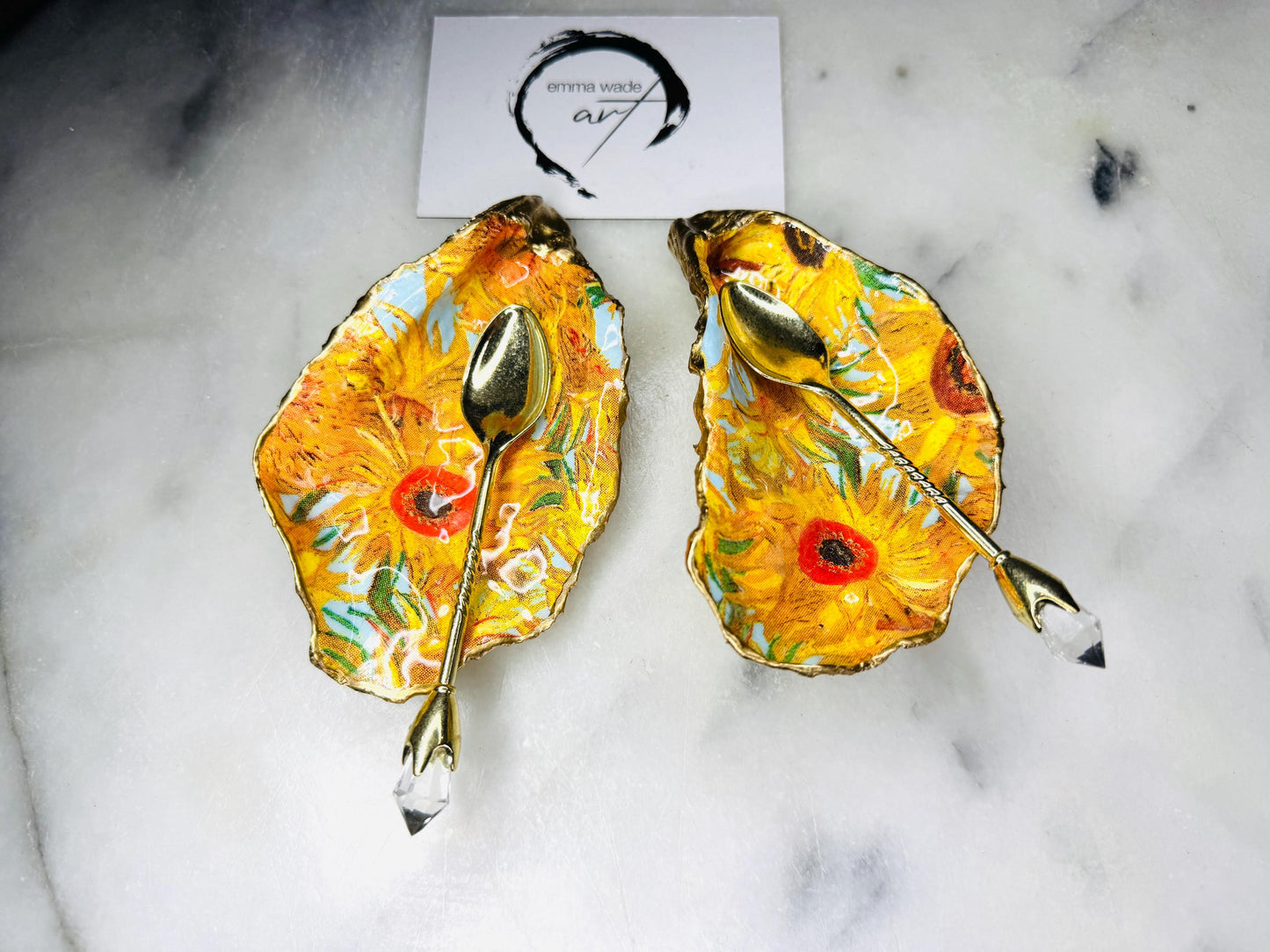 Pair of oyster shell salt and pepper dishes inspired by Vincent Van Gogh Sunflowers. Handmade from natural Dorset shells, each dish is decorated with a sunflower design, trimmed with gold leaf, and sealed for a glossy finish. Approx. 9–10cm with natural variations in shape and depth. Can be used as salt pinch pots, trinket trays, or decorative shell dishes. Optional gold crystal spoons add a luxury touch. A unique handmade gift for weddings, anniversaries, birthdays, or Christmas.