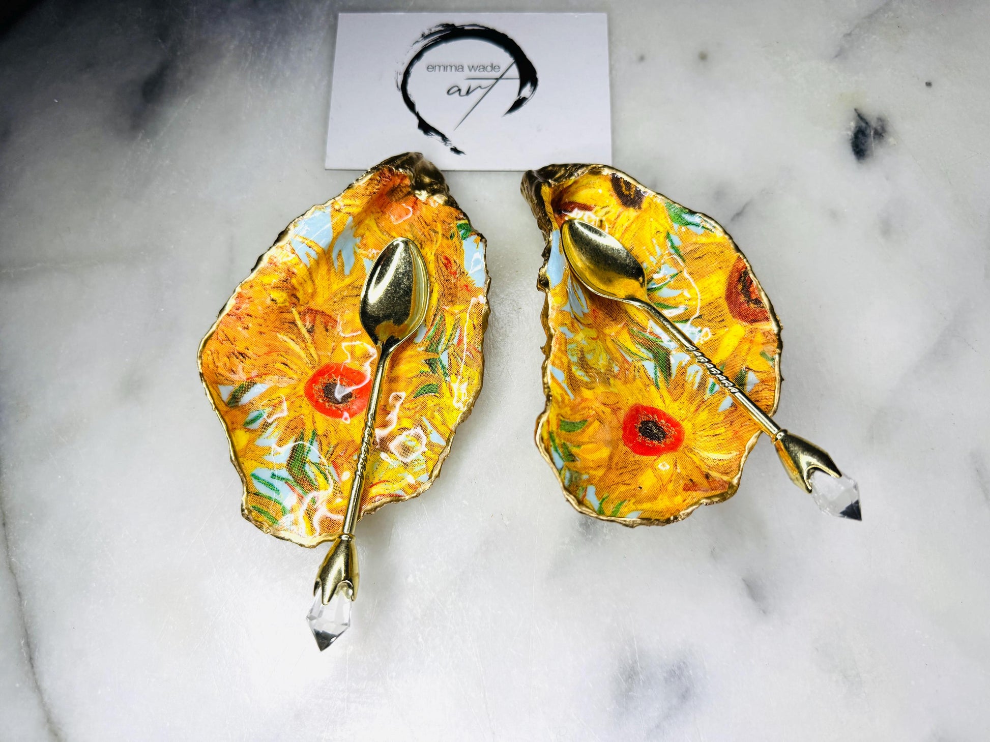 Pair of oyster shell salt and pepper dishes inspired by Vincent Van Gogh Sunflowers. Handmade from natural Dorset shells, each dish is decorated with a sunflower design, trimmed with gold leaf, and sealed for a glossy finish. Approx. 9–10cm with natural variations in shape and depth. Can be used as salt pinch pots, trinket trays, or decorative shell dishes. Optional gold crystal spoons add a luxury touch. A unique handmade gift for weddings, anniversaries, birthdays, or Christmas.