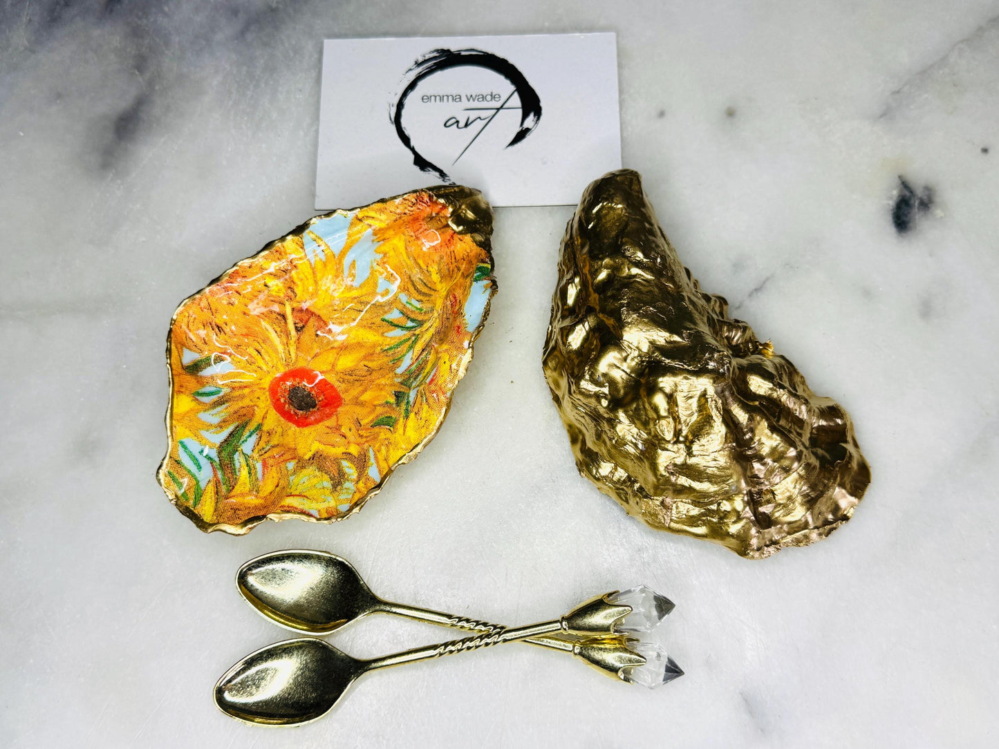 Pair of oyster shell salt and pepper dishes inspired by Vincent Van Gogh Sunflowers. Handmade from natural Dorset shells, each dish is decorated with a sunflower design, trimmed with gold leaf, and sealed for a glossy finish. Approx. 9–10cm with natural variations in shape and depth. Can be used as salt pinch pots, trinket trays, or decorative shell dishes. Optional gold crystal spoons add a luxury touch. A unique handmade gift for weddings, anniversaries, birthdays, or Christmas.