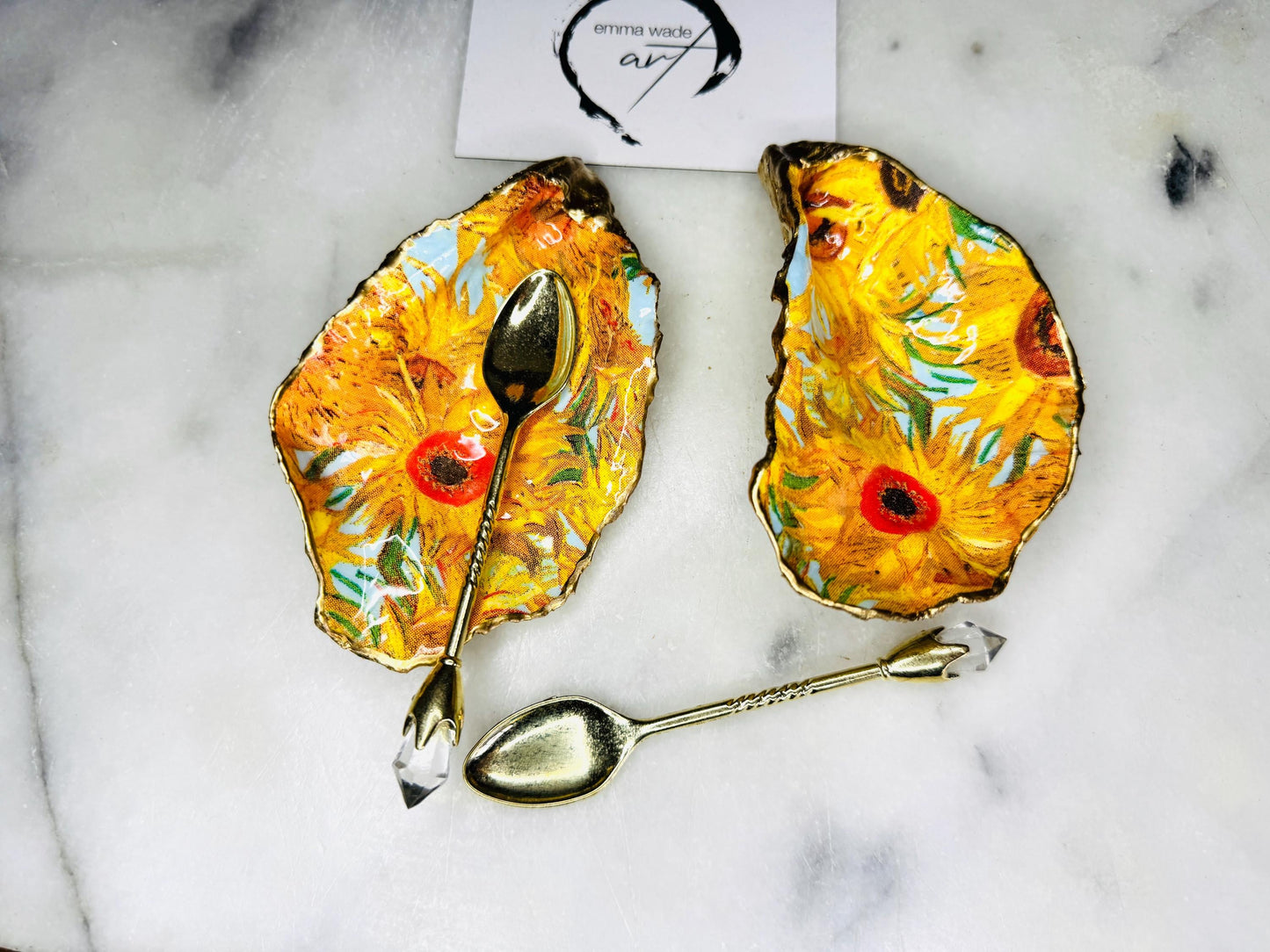 Pair of oyster shell salt and pepper dishes inspired by Vincent Van Gogh Sunflowers. Handmade from natural Dorset shells, each dish is decorated with a sunflower design, trimmed with gold leaf, and sealed for a glossy finish. Approx. 9–10cm with natural variations in shape and depth. Can be used as salt pinch pots, trinket trays, or decorative shell dishes. Optional gold crystal spoons add a luxury touch. A unique handmade gift for weddings, anniversaries, birthdays, or Christmas.