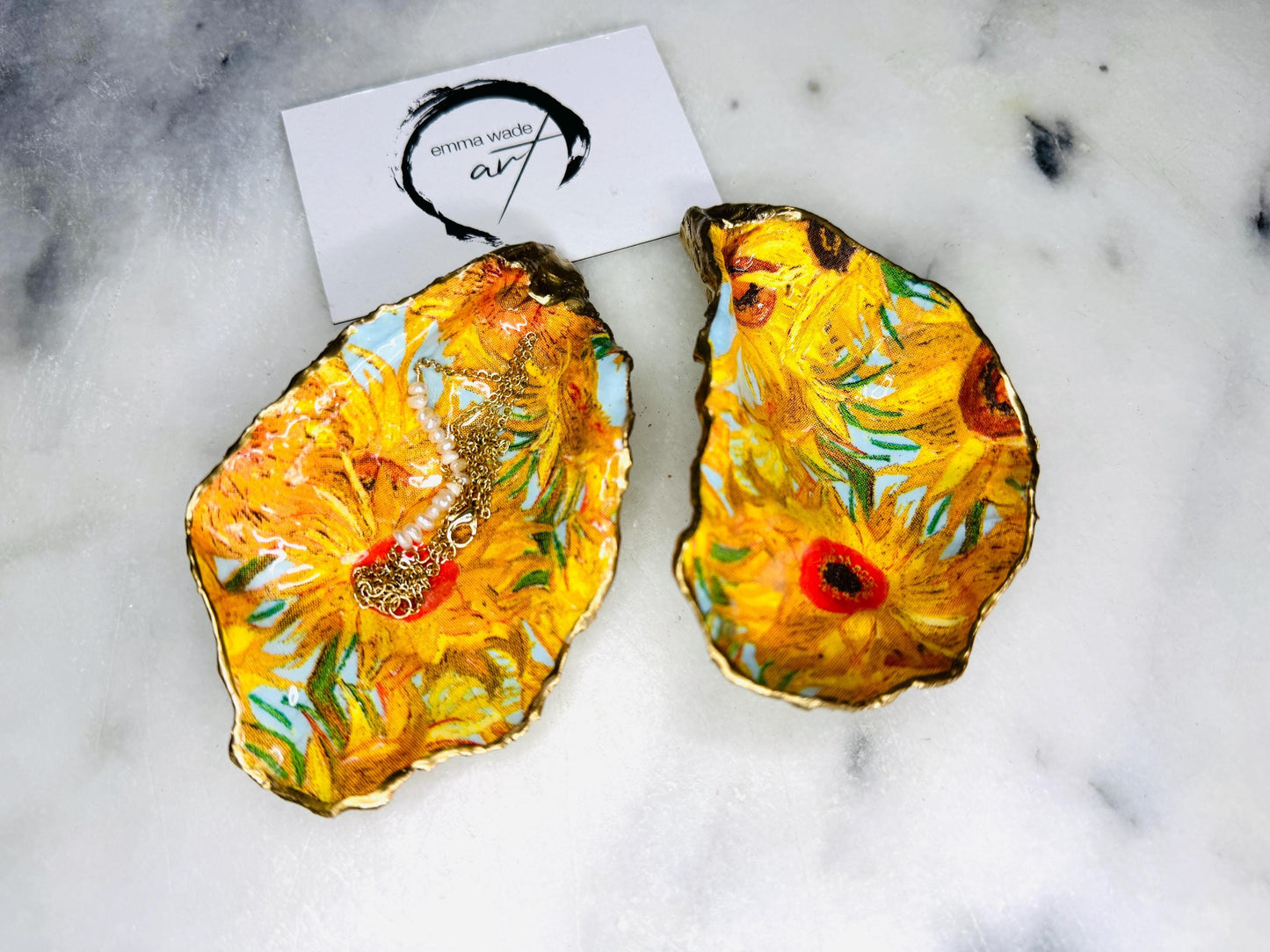 Hand-painted Vincent Van Gogh Sunflowers oyster shell trinket dish with hand-applied liquid gold leaf edging and high gloss resin finish. Natural Dorset oyster shell jewellery holder featuring vibrant yellow sunflower design, styled on marble surface as a ring dish, coastal decor accent and luxury handmade gift.