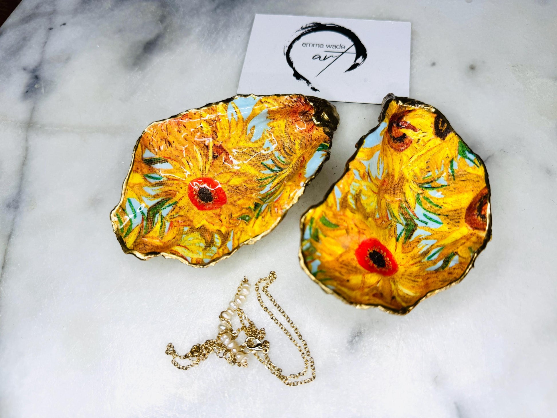Hand-painted Vincent Van Gogh Sunflowers oyster shell trinket dish with hand-applied liquid gold leaf edging and high gloss resin finish. Natural Dorset oyster shell jewellery holder featuring vibrant yellow sunflower design, styled on marble surface as a ring dish, coastal decor accent and luxury handmade gift.