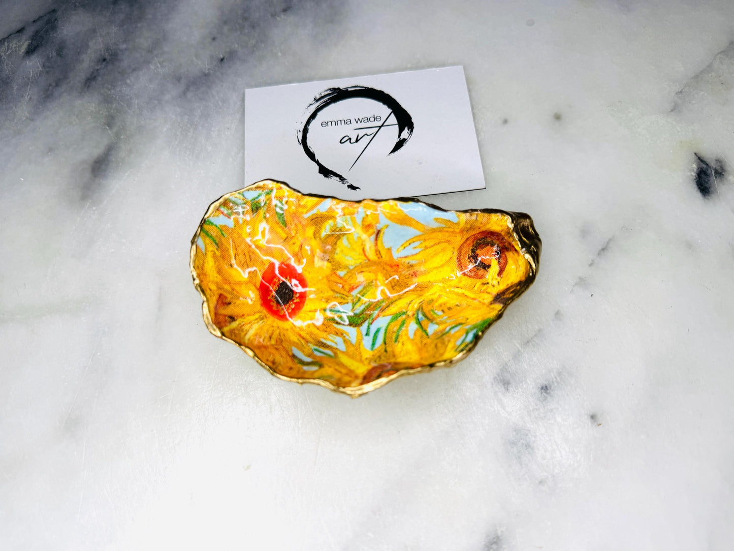 Hand-painted Vincent Van Gogh Sunflowers oyster shell trinket dish with hand-applied liquid gold leaf edging and high gloss resin finish. Natural Dorset oyster shell jewellery holder featuring vibrant yellow sunflower design, styled on marble surface as a ring dish, coastal decor accent and luxury handmade gift.
