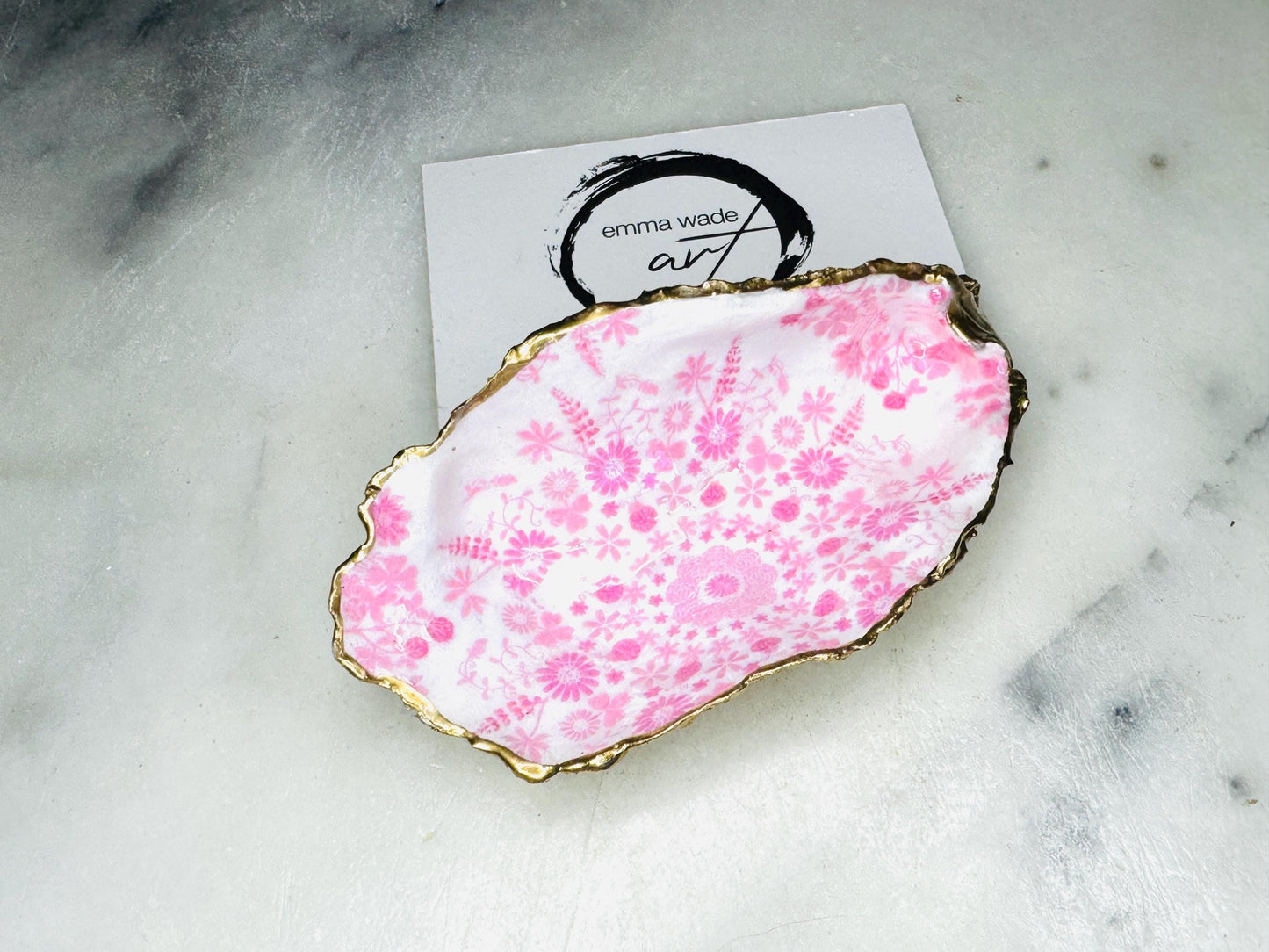 Pink lily oyster shell jewellery dish with gold leaf trim. A unique shell ring holder, trinket dish, or shell ring tray made from natural Dorset shells. Each dish has a floral design and varies slightly in size and shape. Perfect for storing rings, earrings, cufflinks, or small keepsakes. Can also be used as a tealight holder, spoon rest, or salt pinch pot. A beautiful wedding gift, bridesmaid favour, birthday present, or coastal-inspired home accessory.
