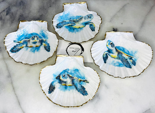 Handmade scallop shell trinket dish featuring a blue sea turtle illustration, finished with high gloss crystal resin and optional gilded gold leaf edges. Coastal home decor shell dish for jewellery, rings, trinkets or bedside storage. Nautical ocean inspired decorative shell, handmade in the UK using sustainably sourced shells from the Dorset coastline. Ideal coastal gift for ocean lovers and beach house interiors.