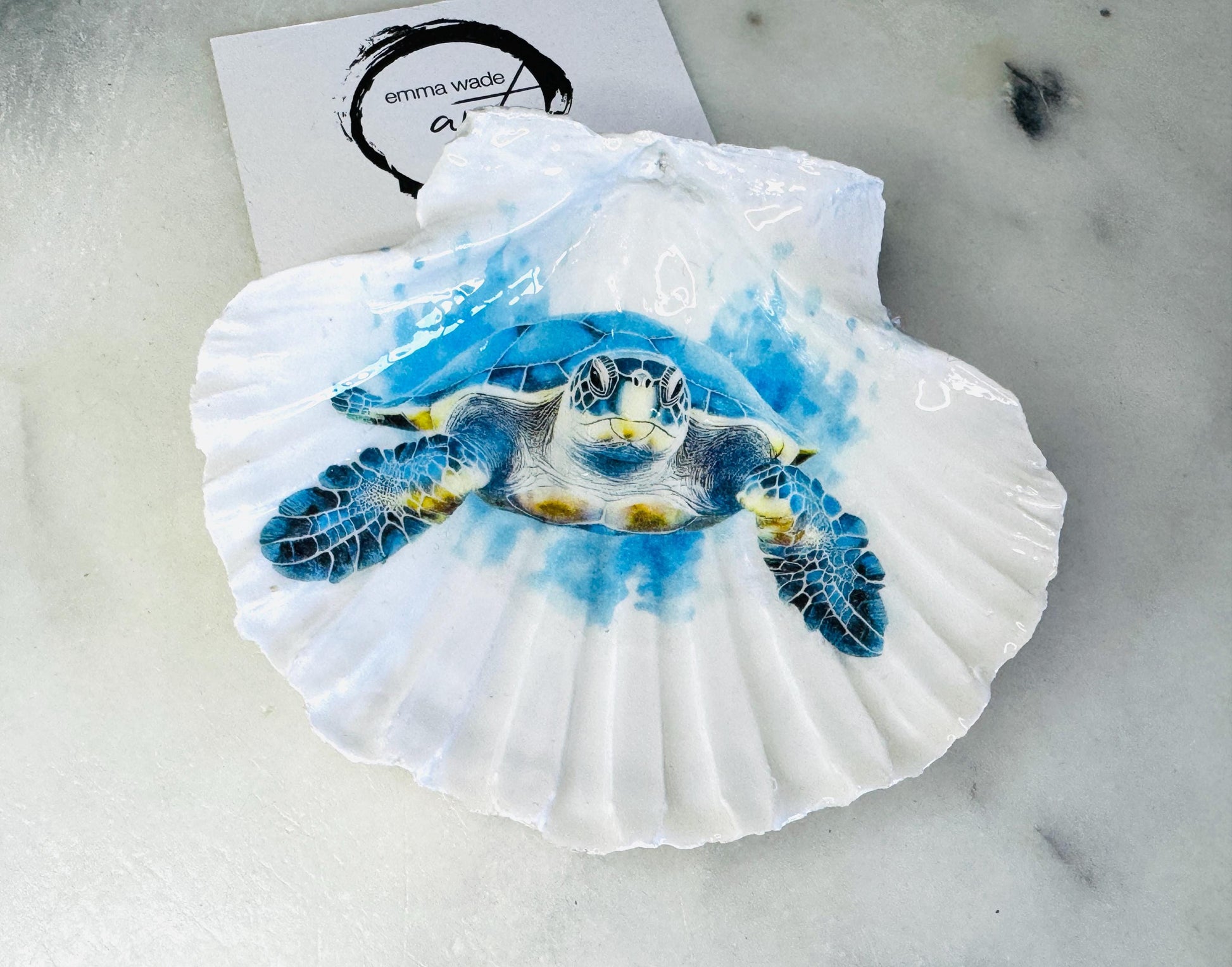 Handmade scallop shell trinket dish featuring a blue sea turtle illustration, finished with high gloss crystal resin and optional gilded gold leaf edges. Coastal home decor shell dish for jewellery, rings, trinkets or bedside storage. Nautical ocean inspired decorative shell, handmade in the UK using sustainably sourced shells from the Dorset coastline. Ideal coastal gift for ocean lovers and beach house interiors.