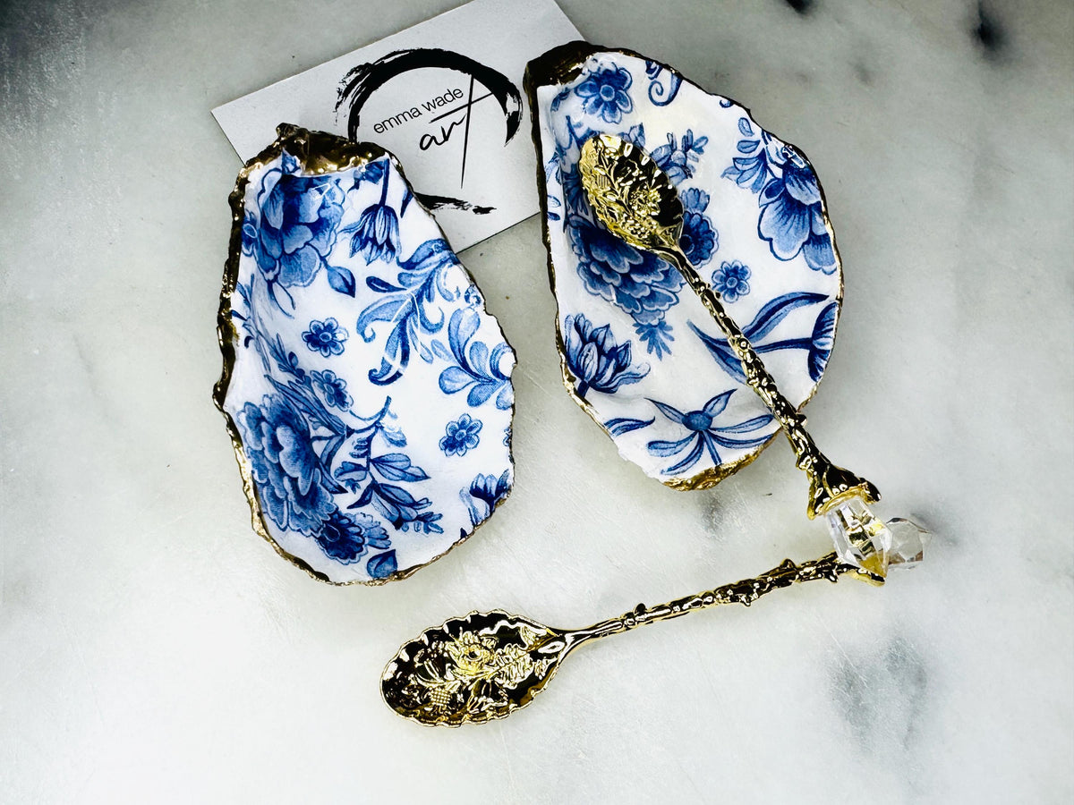 Pair of handmade Delft Blue oyster shell salt cellar set with blue and white floral pattern, gold leaf edging and matching gold crystal spoons. Coastal oyster shell pinch pots finished in glossy resin for elegant table decor