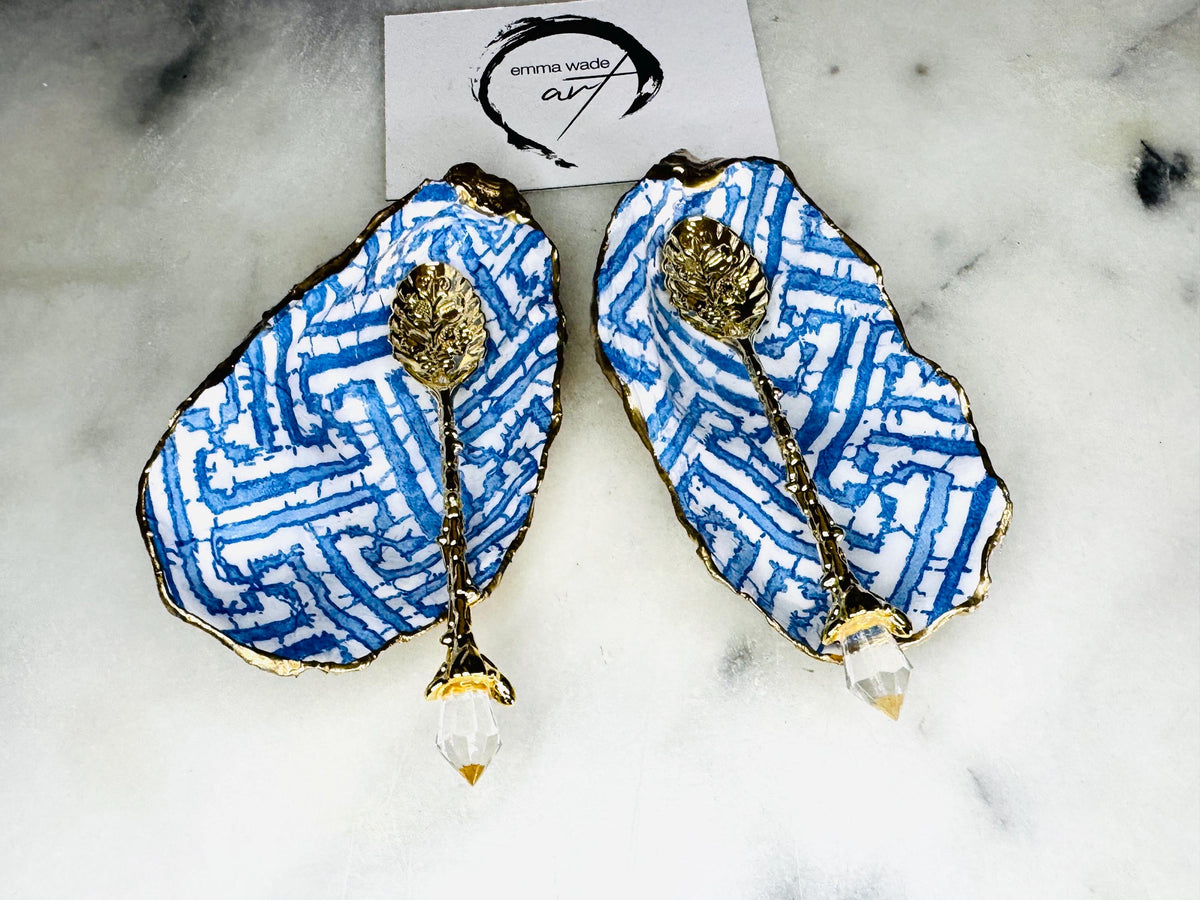 Handmade blue fretwork oyster shell salt and pepper pinch pots shown as a matching pair with small gold spoons, crafted from natural Dorset oyster shells. Each shell features a striking blue fretwork maze pattern, sealed with crystal-clear food-safe resin and finished with shimmering gold leaf edges. Coastal-inspired shell cruet dishes, perfect for table decor, weddings, or a unique luxury hostess gift, with each piece one of a kind.