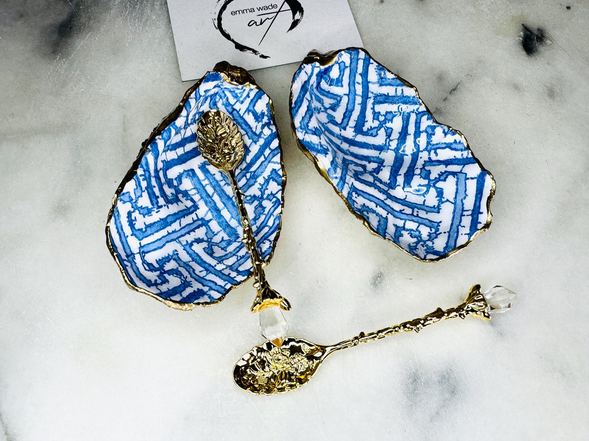 Handmade blue fretwork oyster shell salt and pepper pinch pots shown as a matching pair with small gold spoons, crafted from natural Dorset oyster shells. Each shell features a striking blue fretwork maze pattern, sealed with crystal-clear food-safe resin and finished with shimmering gold leaf edges. Coastal-inspired shell cruet dishes, perfect for table decor, weddings, or a unique luxury hostess gift, with each piece one of a kind.