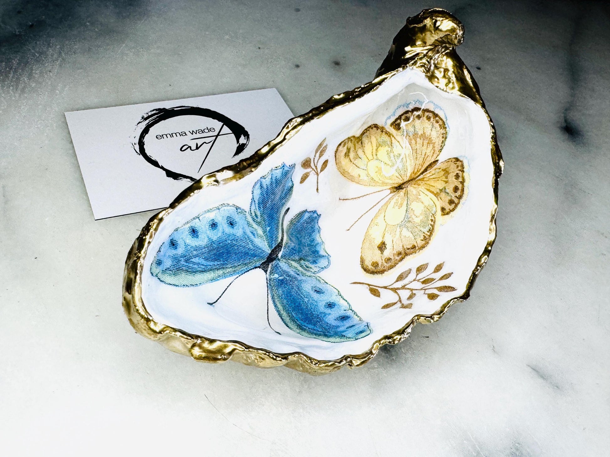 Blue yellow green butterfly oyster shell trinket dish handmade from Dorset coast shell, gold leaf gilded rim and back, high gloss resin interior with colourful butterfly design, coastal home decor jewellery dish, ring holder, trinket tray, seaside gift for her, handmade shell decor, luxury coastal accessory, unique artisan gift UK