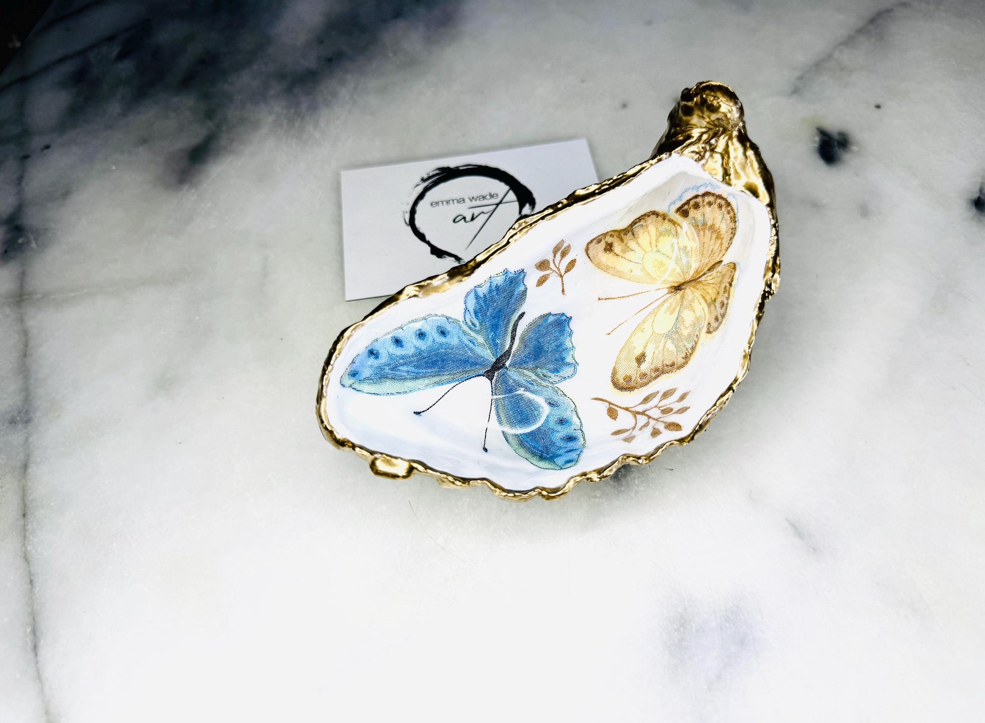 Blue yellow green butterfly oyster shell trinket dish handmade from Dorset coast shell, gold leaf gilded rim and back, high gloss resin interior with colourful butterfly design, coastal home decor jewellery dish, ring holder, trinket tray, seaside gift for her, handmade shell decor, luxury coastal accessory, unique artisan gift UK