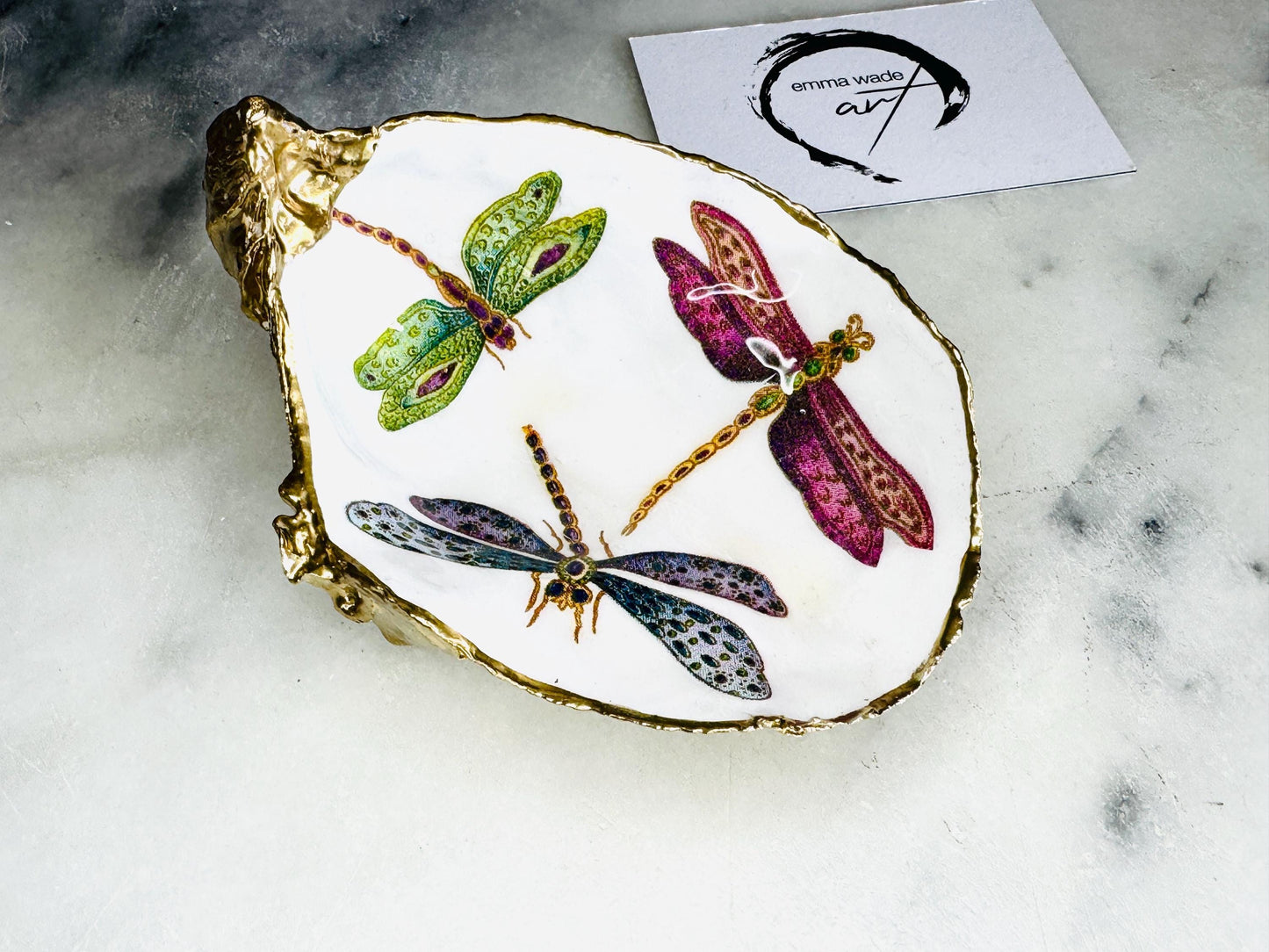 Handmade dragonfly oyster shell trinket dish with hand-gilded gold leaf edges and glossy resin finish, created from sustainably sourced Dorset shells. Unique coastal jewellery holder and ring dish, ideal as a vanity tray, trinket tray or decorative keepsake. Nature inspired home decor gift for birthdays, weddings, anniversaries, housewarmings and Mother’s Day. One of a kind artisan shell dish, beautifully presented in a gift box.