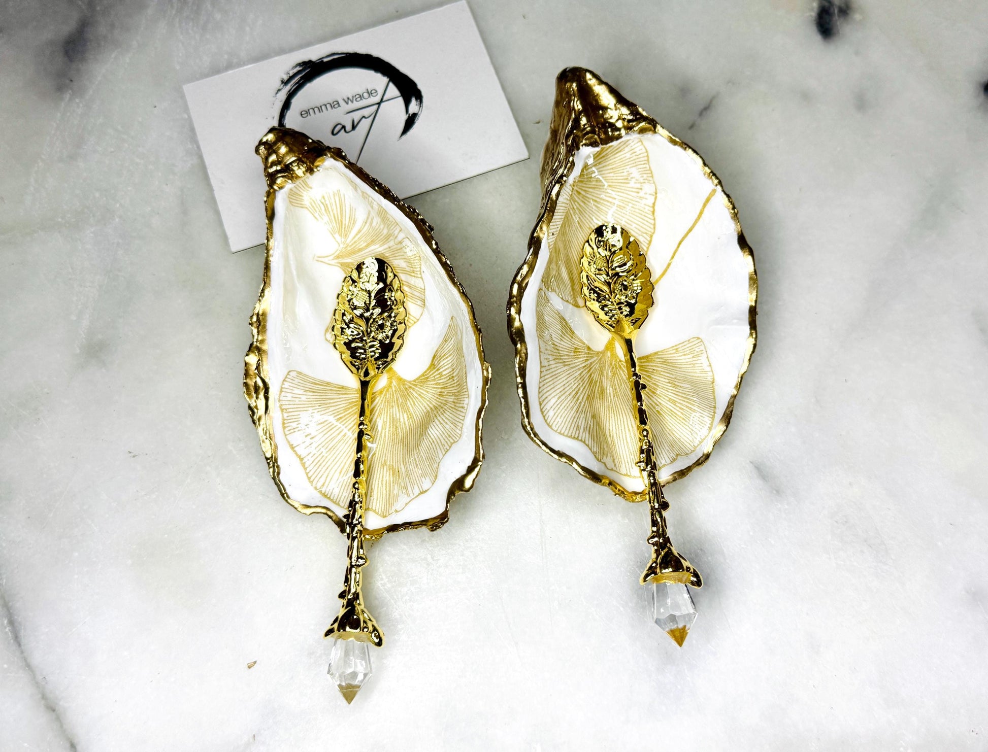 Pair of handmade Dorset oyster shell salt and pepper pinch pots featuring elegant Japanese Ginkgo floral artwork in soft gold and pearl tones with hand-applied gold leaf edging. Coastal luxury cruet set sealed in glossy Crystal resin with optional gold crystal spoons.