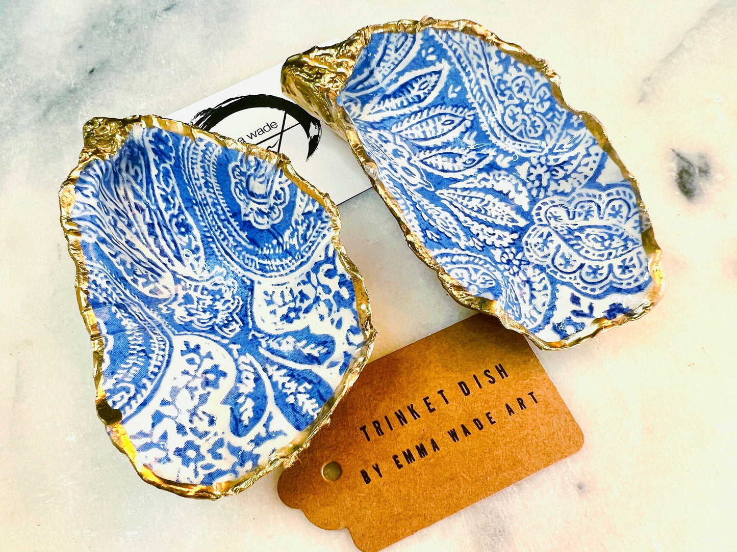 Handmade Dorset oyster shell trinket dish featuring an elegant blue and white paisley design, hand-gilded with liquid gold leaf and finished in glossy resin. Coastal shell jewellery holder available in multiple sizes from small to XL, ideal as a ring dish, trinket tray, vanity decor, or luxury coastal gift.