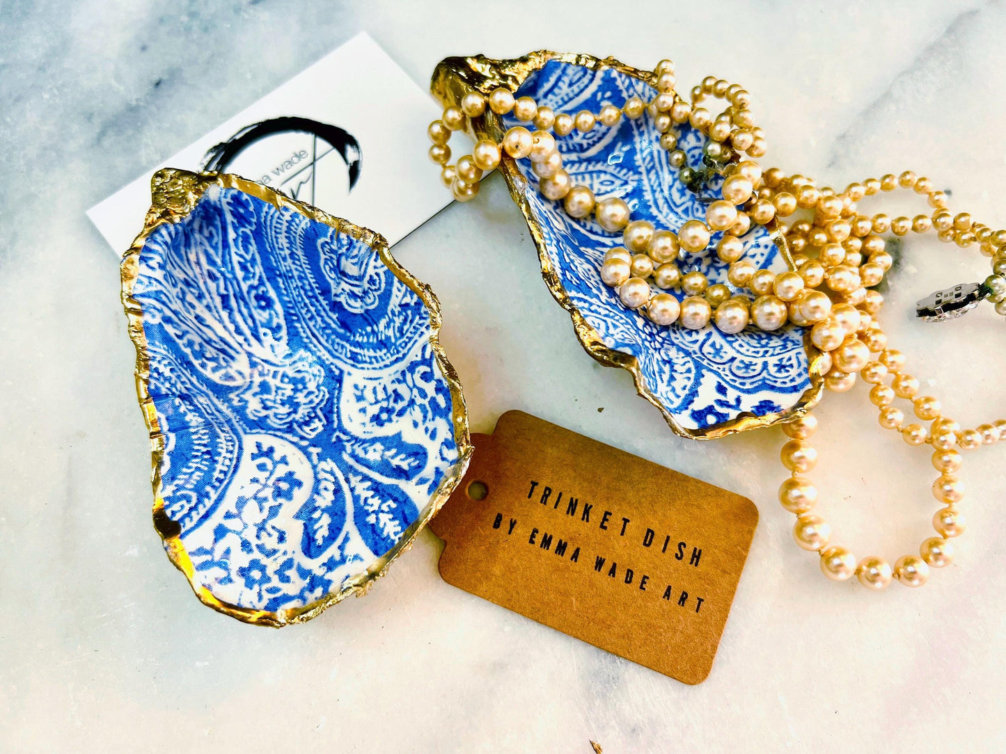Handmade Dorset oyster shell trinket dish featuring an elegant blue and white paisley design, hand-gilded with liquid gold leaf and finished in glossy resin. Coastal shell jewellery holder available in multiple sizes from small to XL, ideal as a ring dish, trinket tray, vanity decor, or luxury coastal gift.