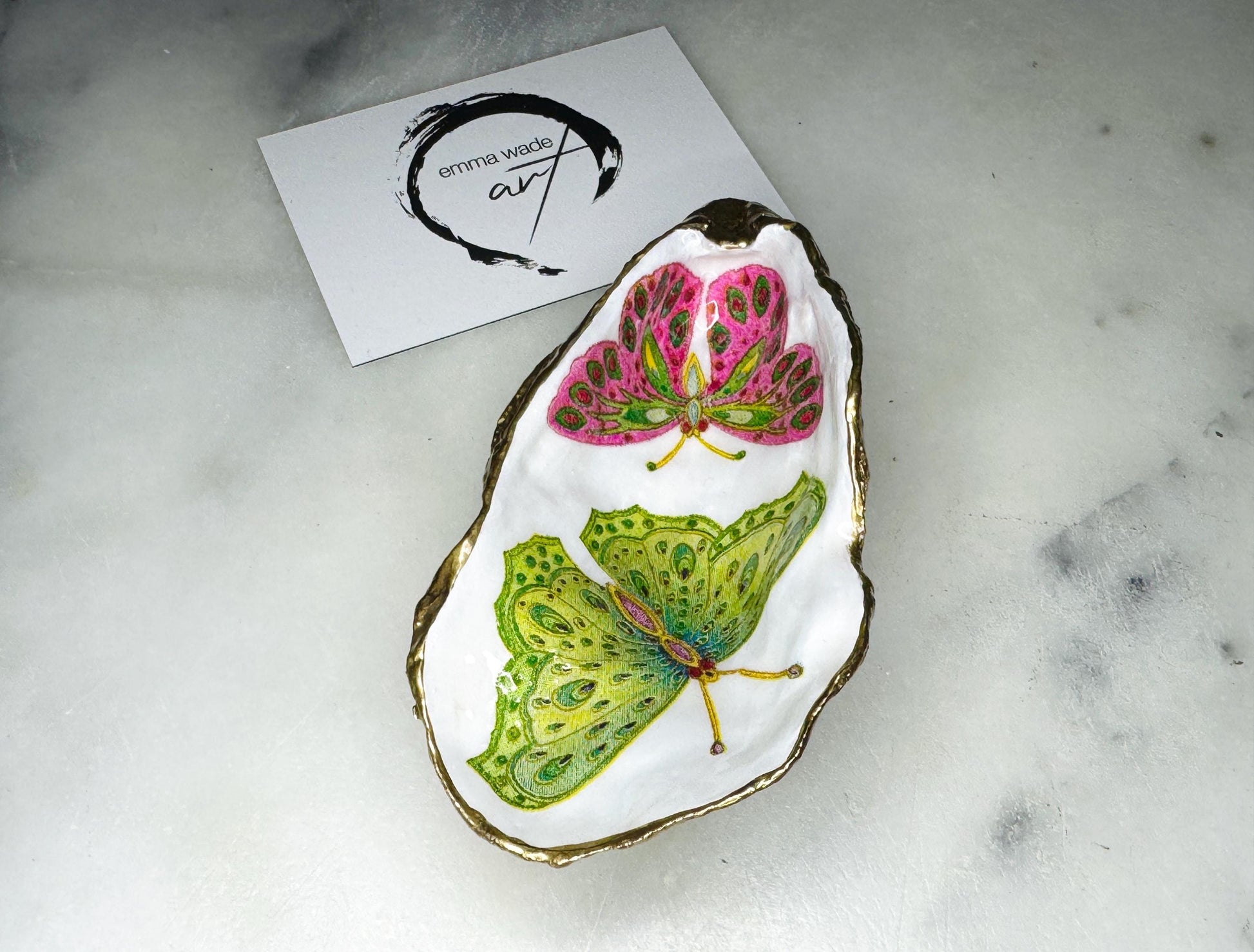 Handmade butterfly oyster shell trinket dish with colourful blue green and pink butterfly designs, edged and backed in gold leaf, Dorset coastal shell jewellery holder with glossy resin finish, luxury ring dish, coastal home decor gift, unique handmade shell dish for jewellery storage, beach house accessory, UK artisan oyster shell dish