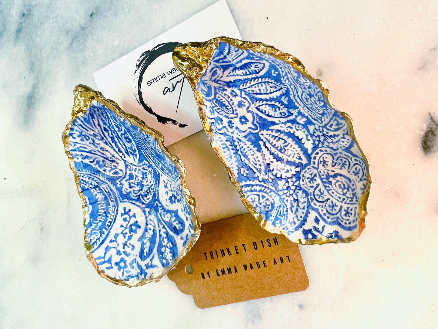 Handmade Dorset oyster shell trinket dish featuring an elegant blue and white paisley design, hand-gilded with liquid gold leaf and finished in glossy resin. Coastal shell jewellery holder available in multiple sizes from small to XL, ideal as a ring dish, trinket tray, vanity decor, or luxury coastal gift.