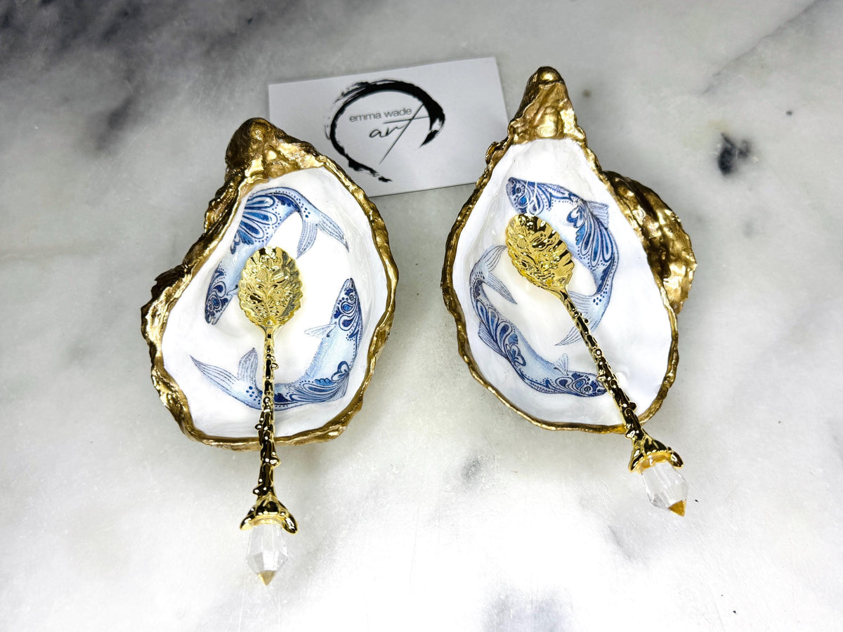 Handmade Dorset oyster shell salt and pepper pinch pots featuring blue paisley fish designs with gold leaf edging and glossy resin finish. Coastal oyster shell cruet set with natural pearlescent interiors and optional gold spoons, styled as elegant nautical table décor and condiment dishes.