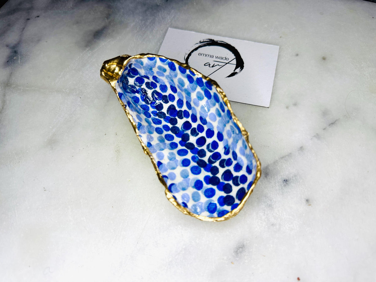 Handmade Emma Bridgewater Blue Dots oyster shell trinket dish, shown as a single jewellery tray with a blue and white dot pattern and hand-gilded gold leaf edges. Crafted from a natural Dorset oyster shell and sealed with glossy, crystal-clear resin. Coastal-inspired home decor, perfect for holding rings, earrings and small keepsakes, with each shell one of a kind and finished by hand.