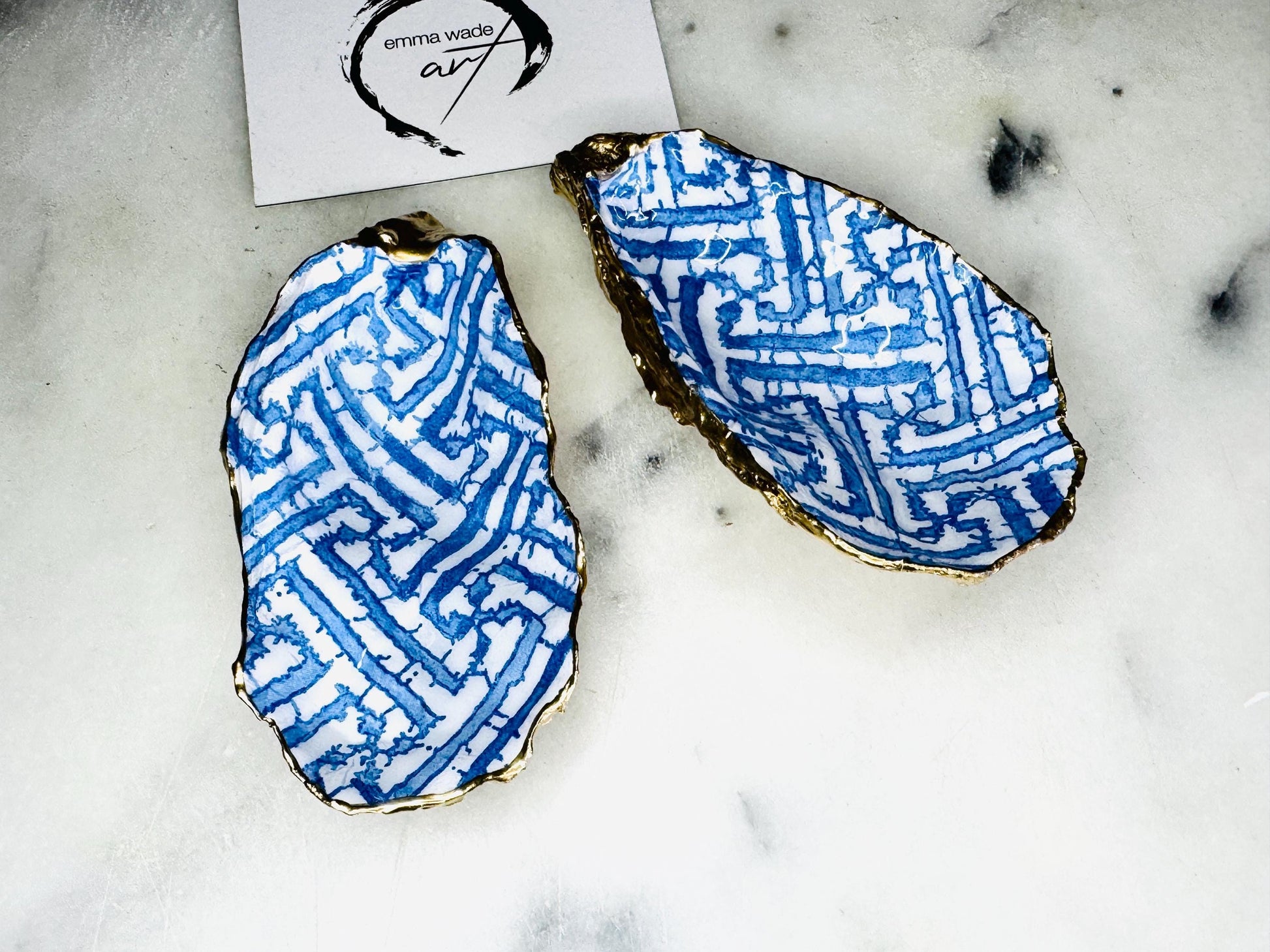 Handmade blue fretwork oyster shell trinket dish shown as a single piece, crafted from a natural Dorset oyster shell and finished with genuine gold leaf edges and glossy resin. Featuring an intricate blue fretwork pattern, this jewellery and ring holder is perfect for a bedside table, bathroom or coastal-inspired decor. Each shell is one of a kind and carefully finished by hand.