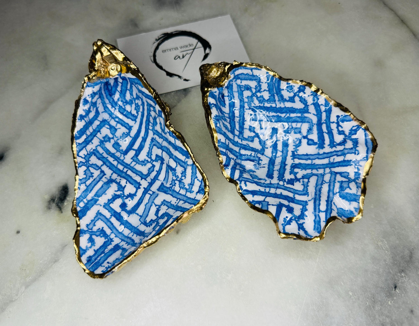 Handmade blue fretwork oyster shell trinket dish shown as a single piece, crafted from a natural Dorset oyster shell and finished with genuine gold leaf edges and glossy resin. Featuring an intricate blue fretwork pattern, this jewellery and ring holder is perfect for a bedside table, bathroom or coastal-inspired decor. Each shell is one of a kind and carefully finished by hand.