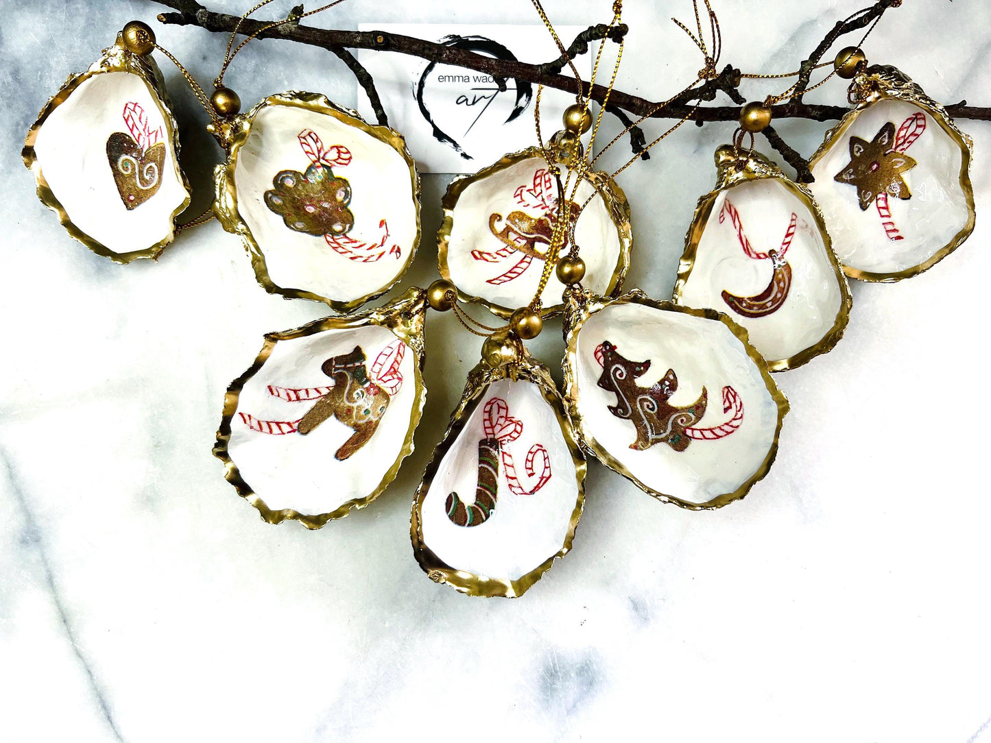 Handcrafted Dorset oyster shell Christmas ornaments featuring gingerbread-inspired festive motifs including candy canes, stars, moons, hearts, and skates. Gold leaf edged coastal Christmas baubles with glossy resin finish and pearl shell interiors displayed as luxury handmade holiday decorations.